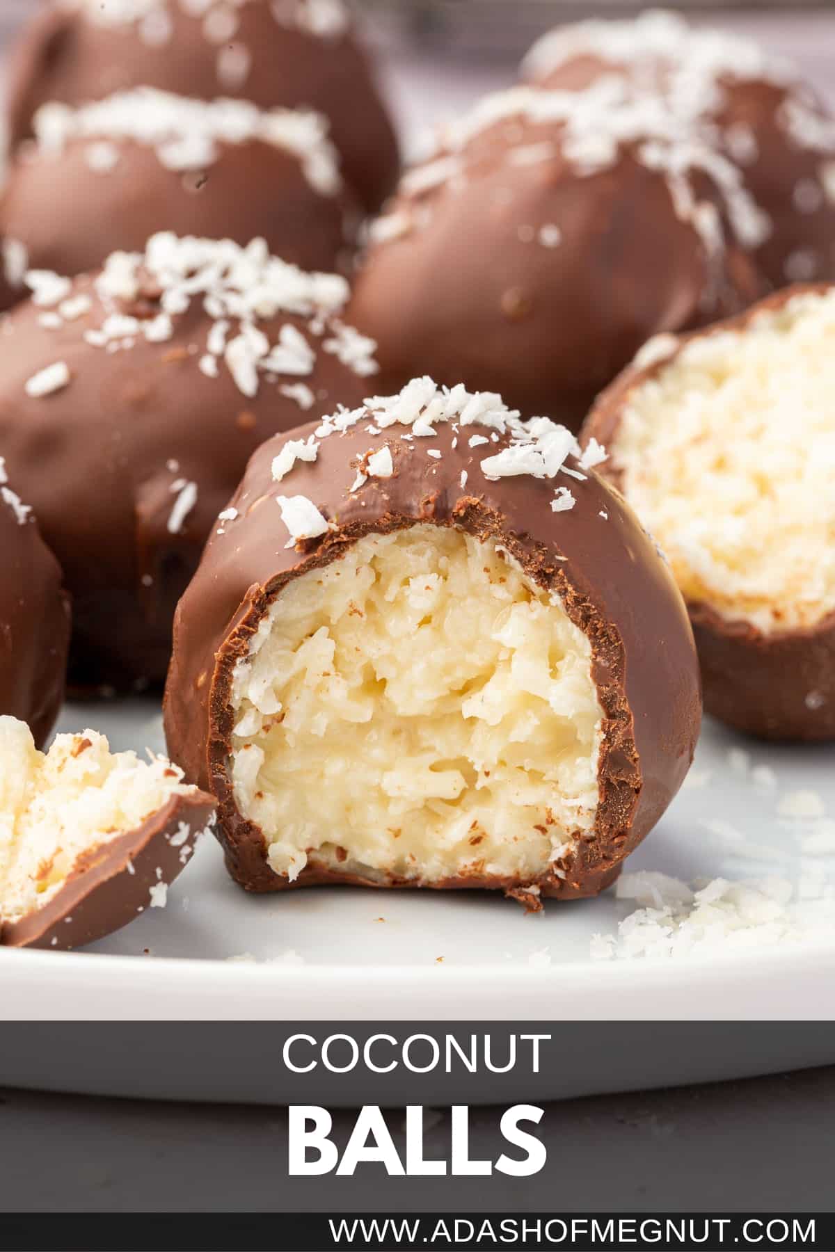 A chocolate covered coconut truffle with a bite taken out of it with additional coconut balls in the background.