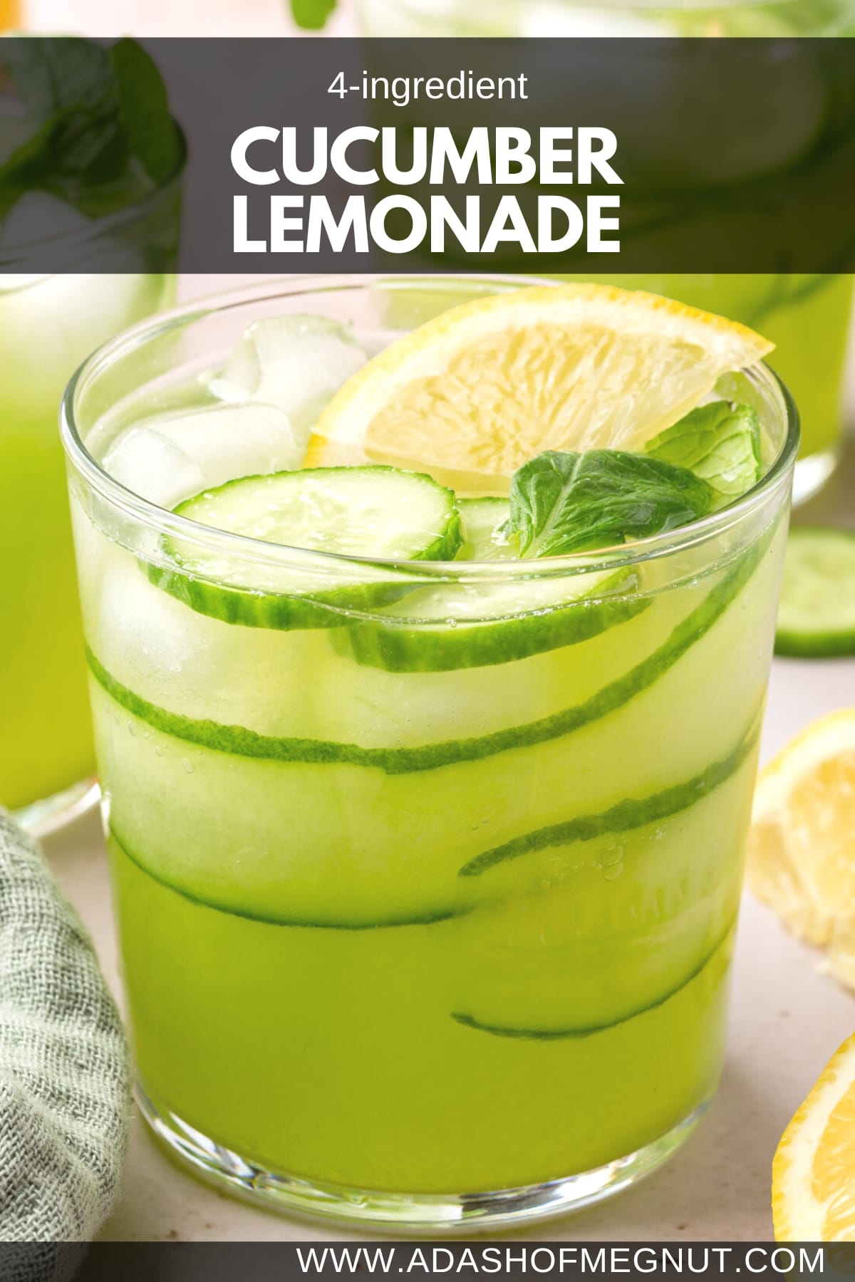 A glass of cucumber lemonade with a wedge of lemon, cucumber slices, cucumber ribbons and fresh mint.