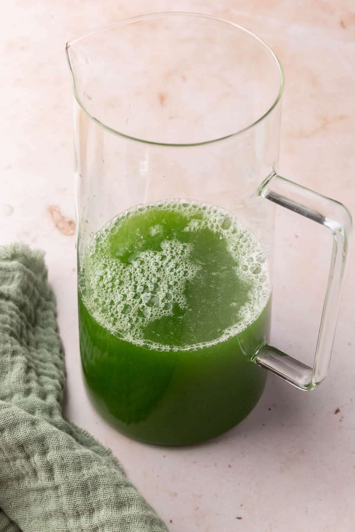 A pitcher with a cucumber juice and lemonade concentrate in it.