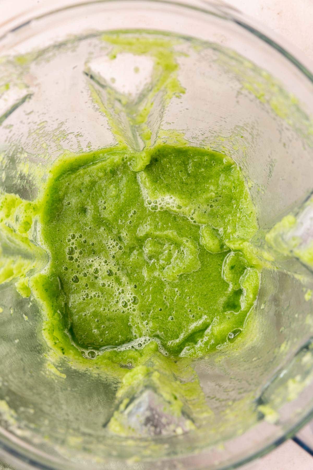 A Vitamix blender with blended cucumber in it.