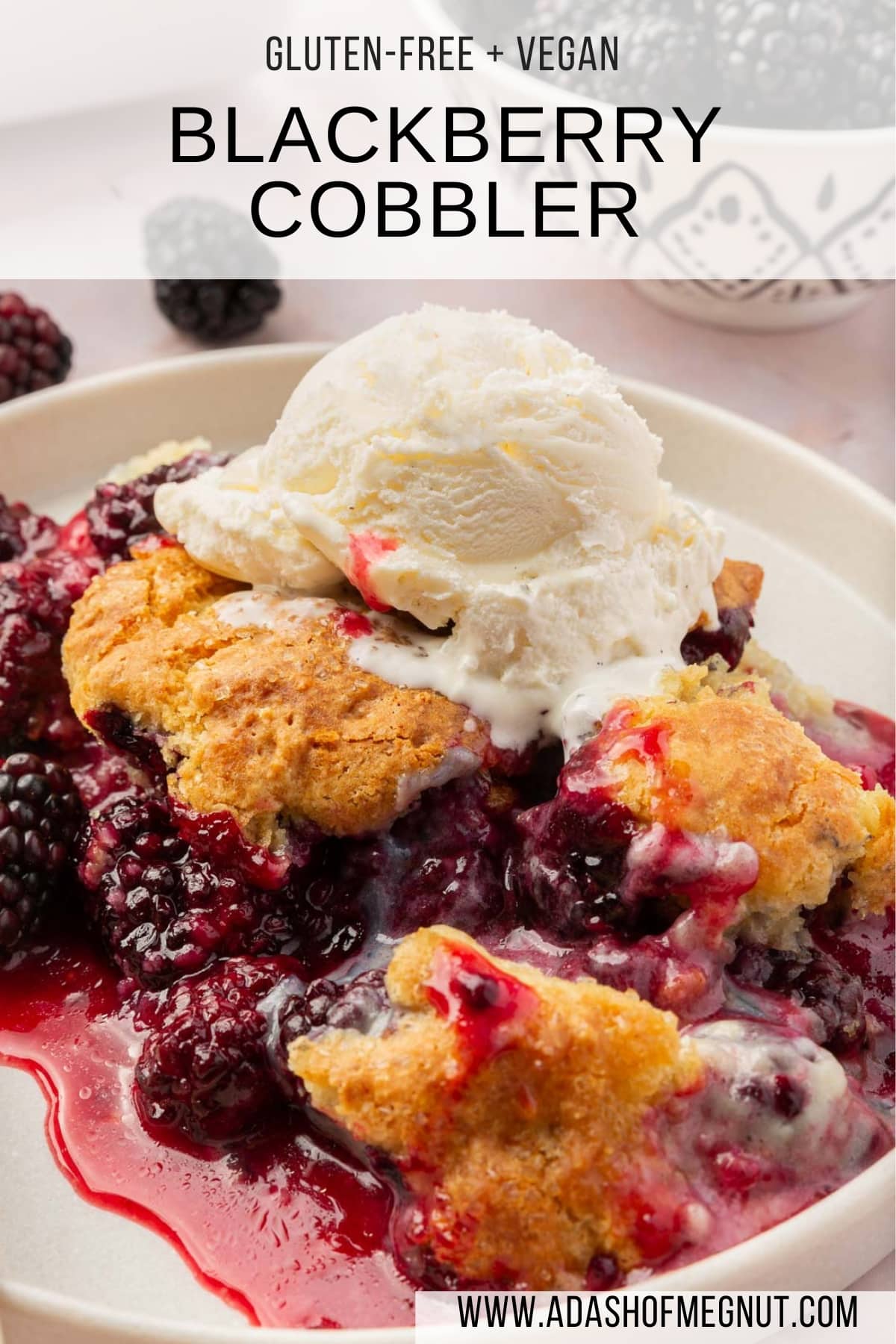 A single serving of gluten-free blackberry cobbler on a plate with a scoop of vanilla ice cream on top and a bowl of blackberries in the background.