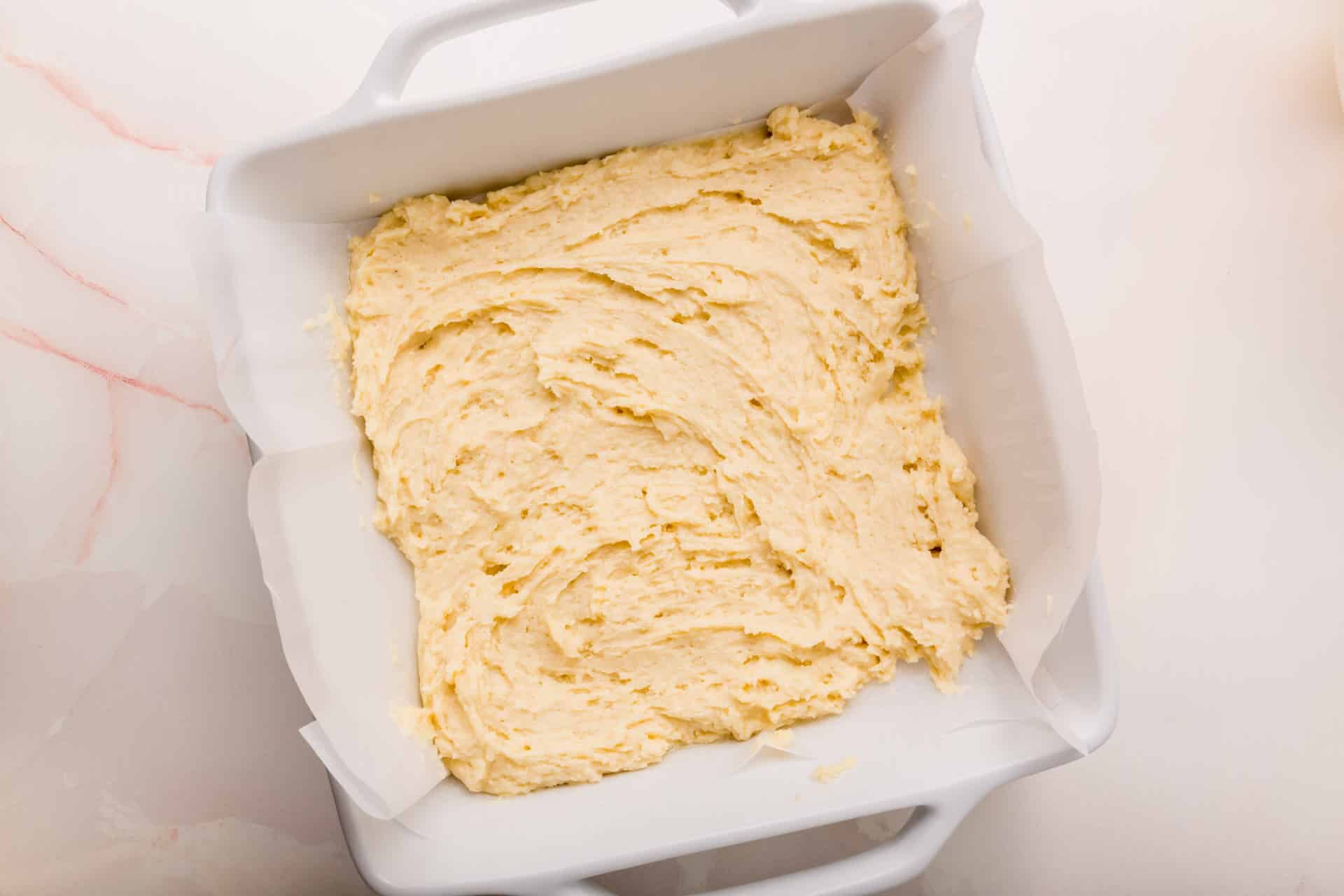 A square baking dish of coffee cake batter that has been spread evenly in the pan.