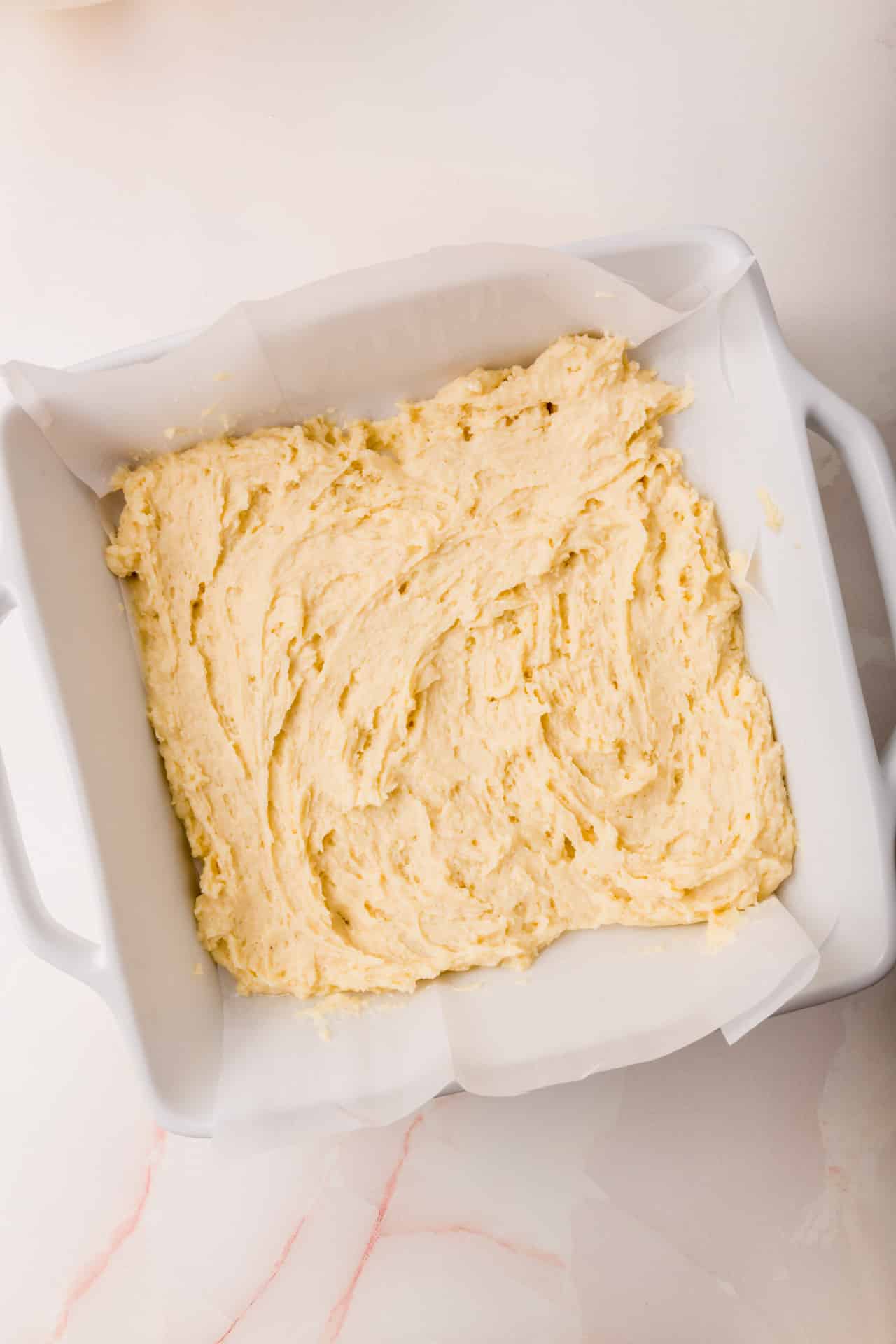 A square baking dish of coffee cake batter that has been spread evenly in the pan.