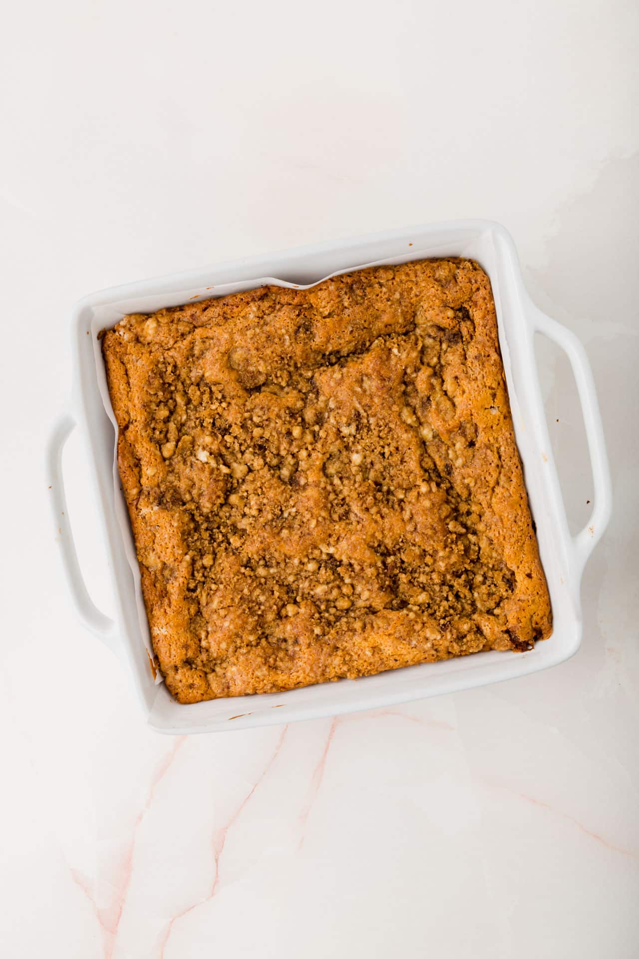 A square baking dish filled with a gluten-free coffee cake with streusel.
