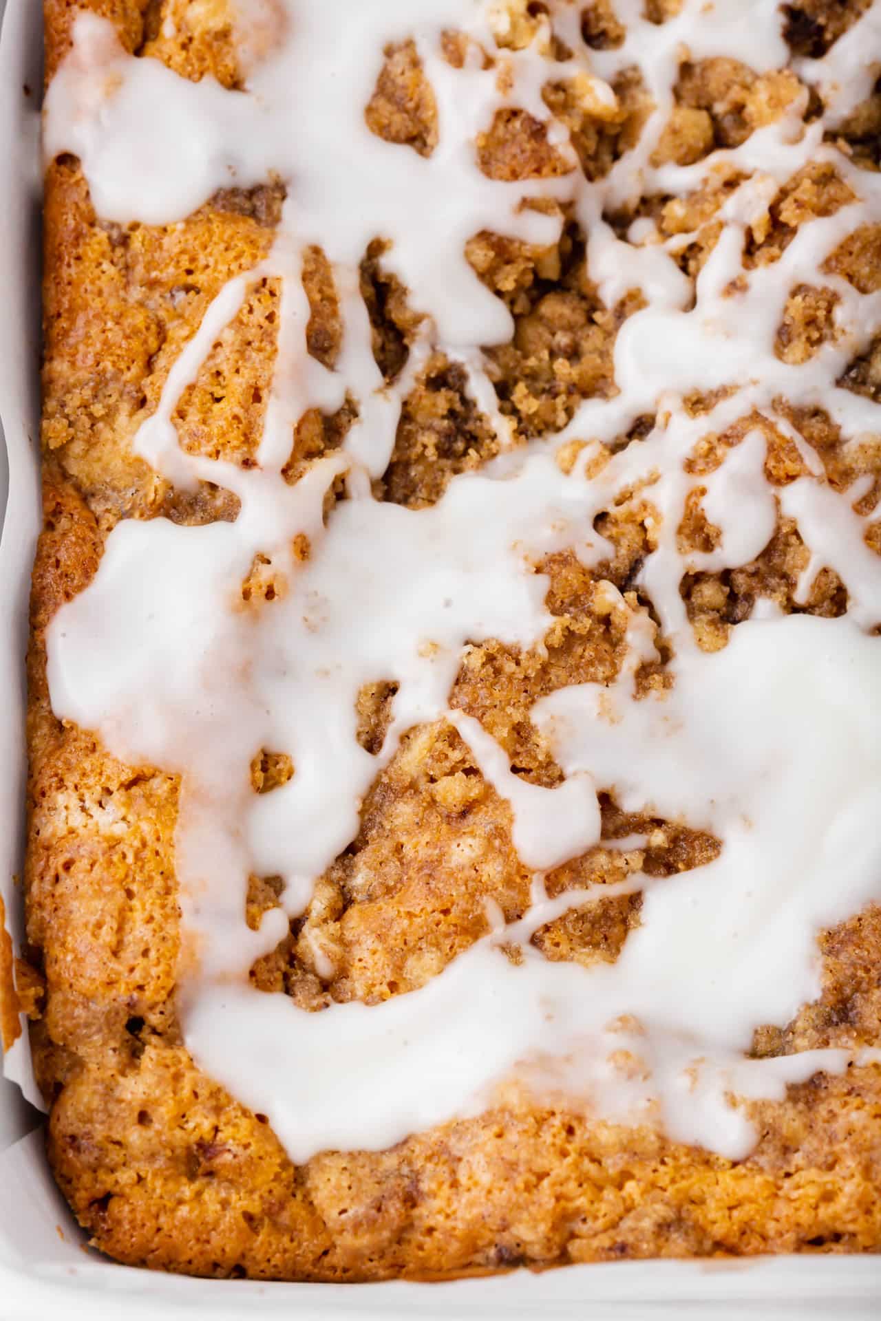 A close up of a gluten-free coffee cake with a powdered sugar glazed drizzled over the top.