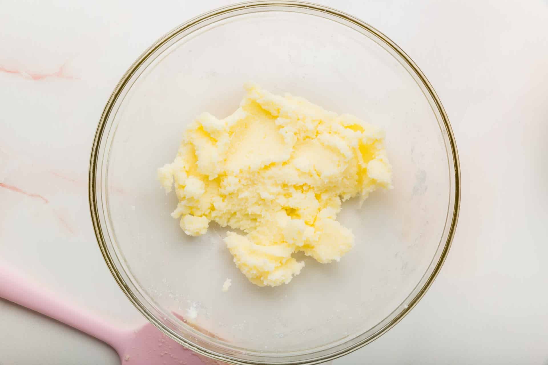A glass mixing bowl with a creamed butter and sugar mixture.