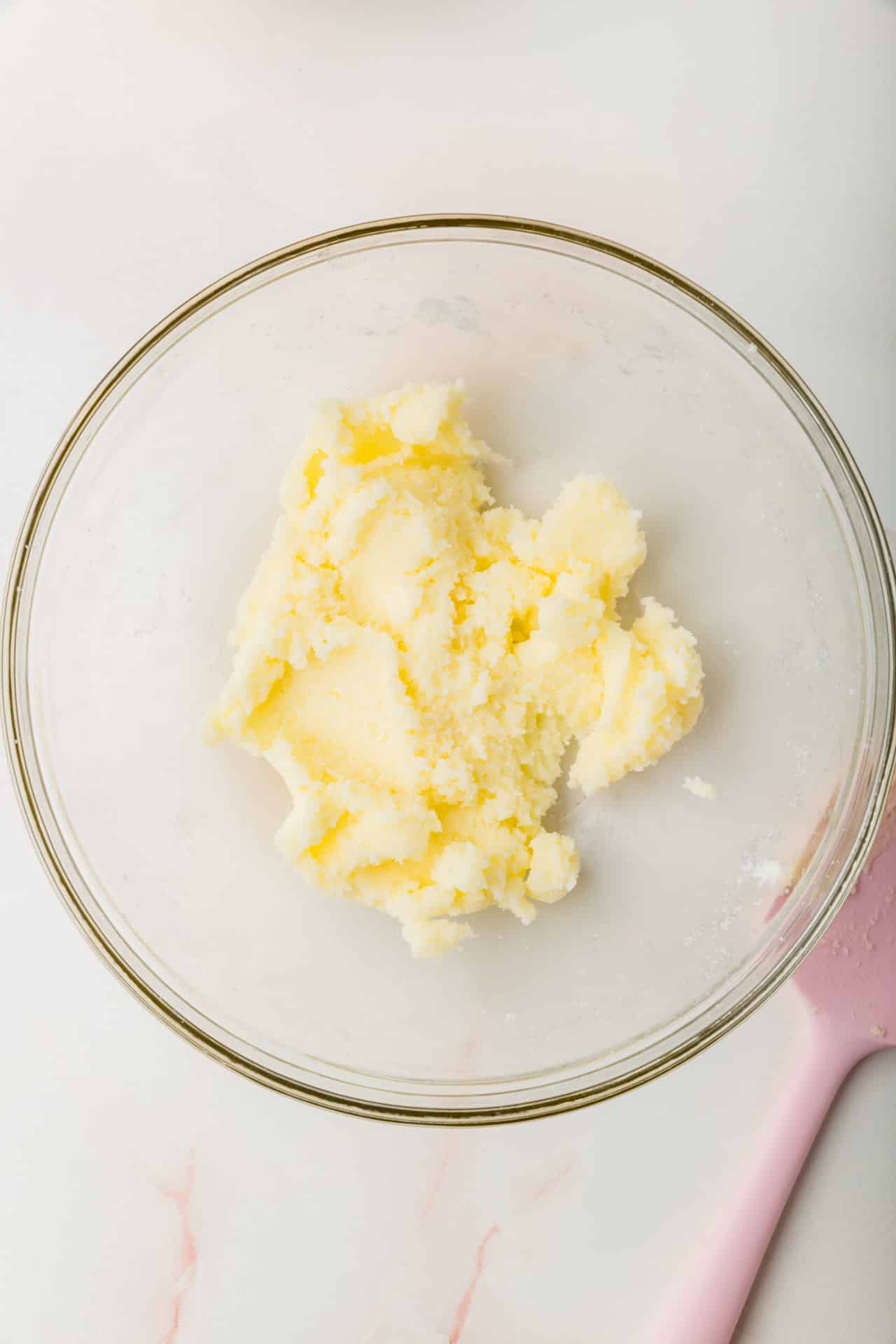 A glass mixing bowl with a creamed butter and sugar mixture.