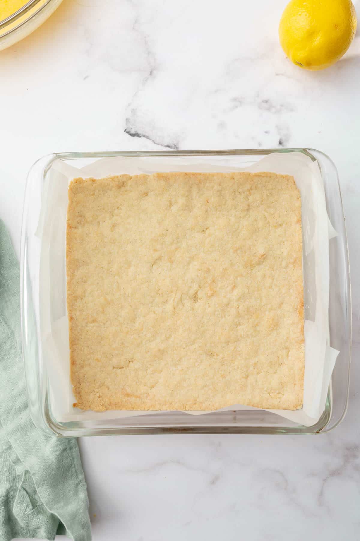 An overhead view of gluten free shortbread crust in a glass baking dish to make gluten free lemon bars.