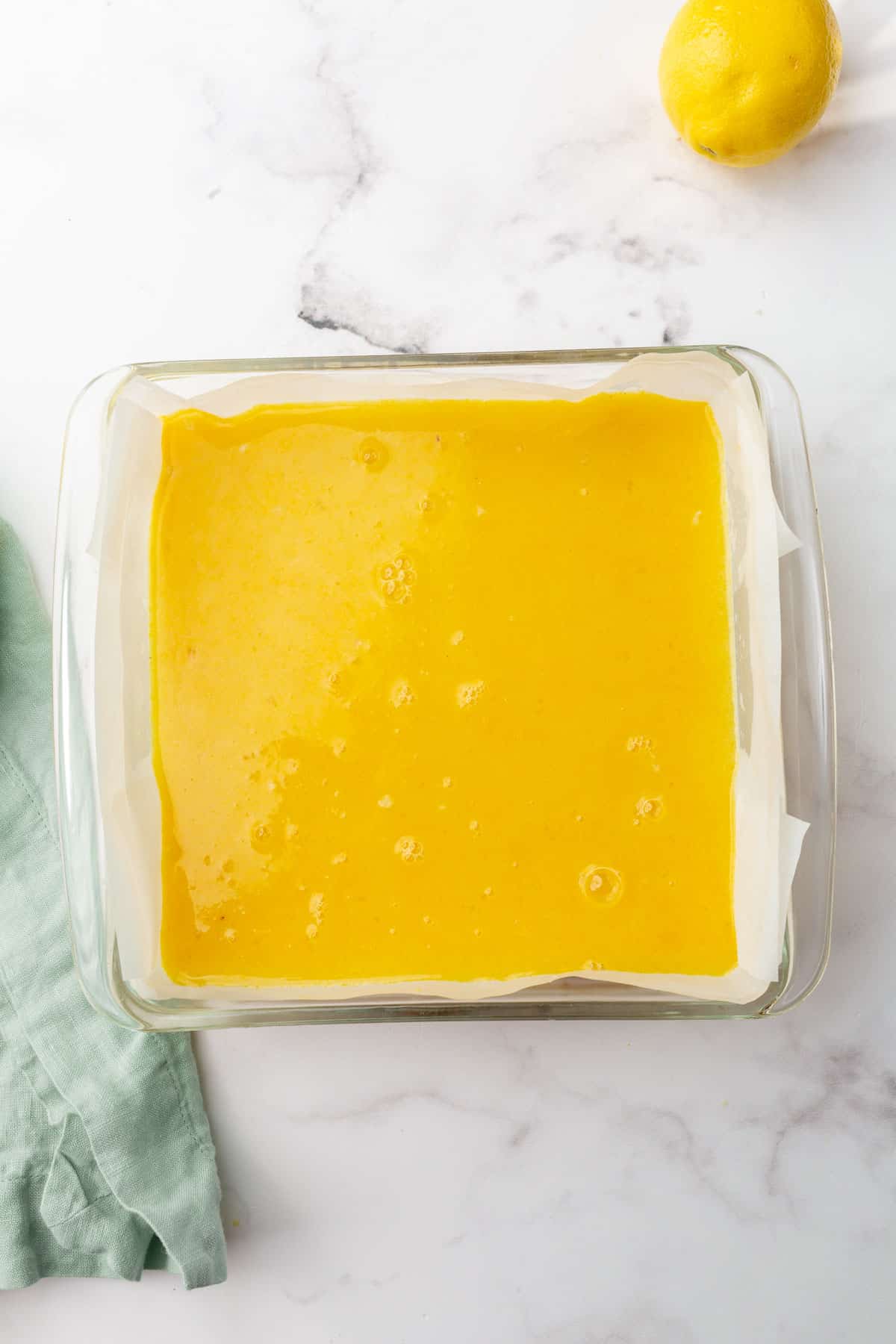 An overhead view of a square glass baking dish with unbaked lemon bar filling in it.