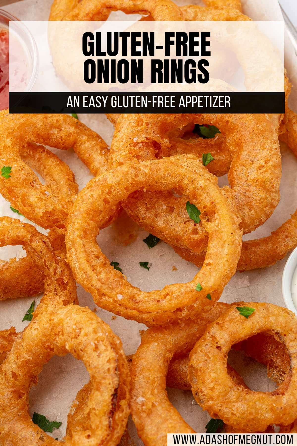 A close up of gluten free onion rings topped with fresh parsley and flaky sea salt on parchment paper.