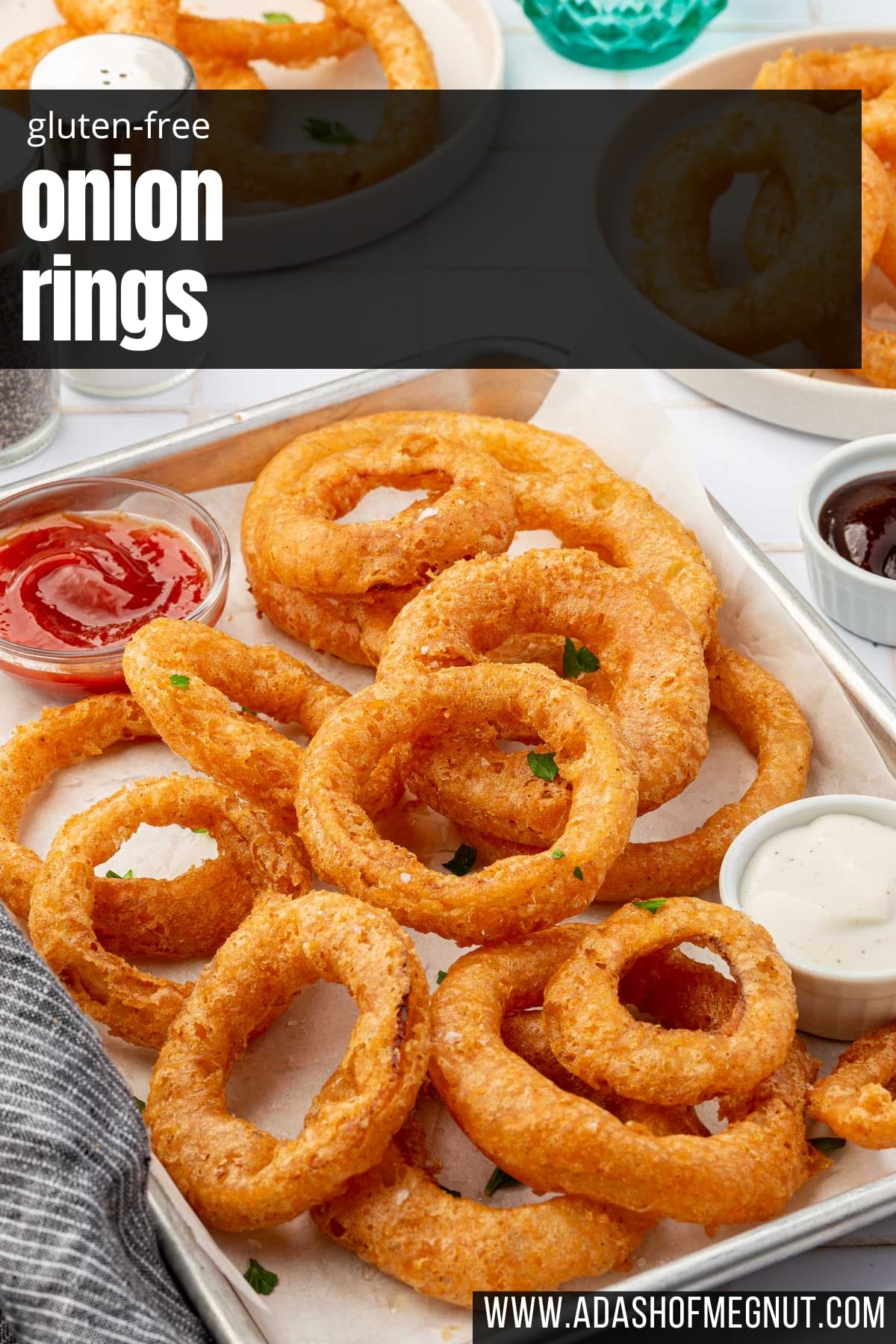 GF onion rings on a baking sheet with bowls of ranch and ketchup.