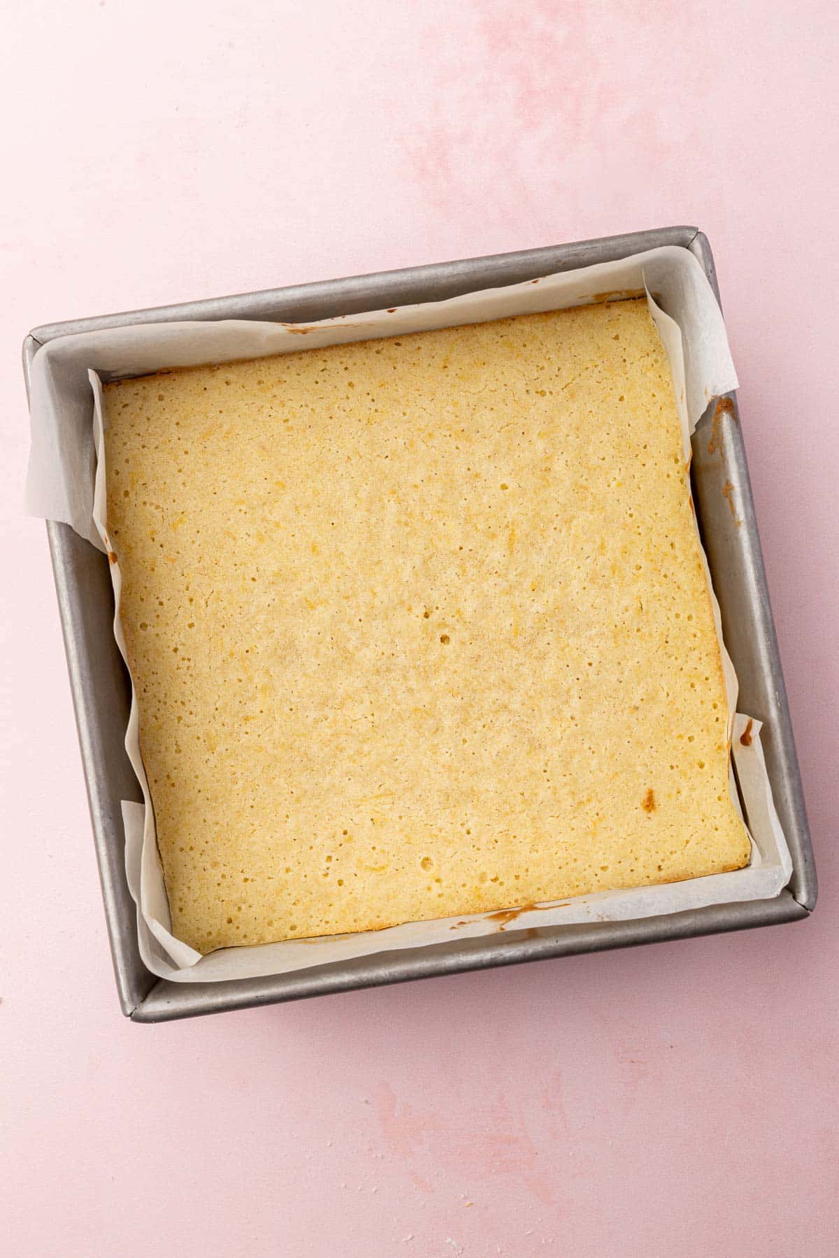 A square metal baking dish with baked lemon brownies in it.