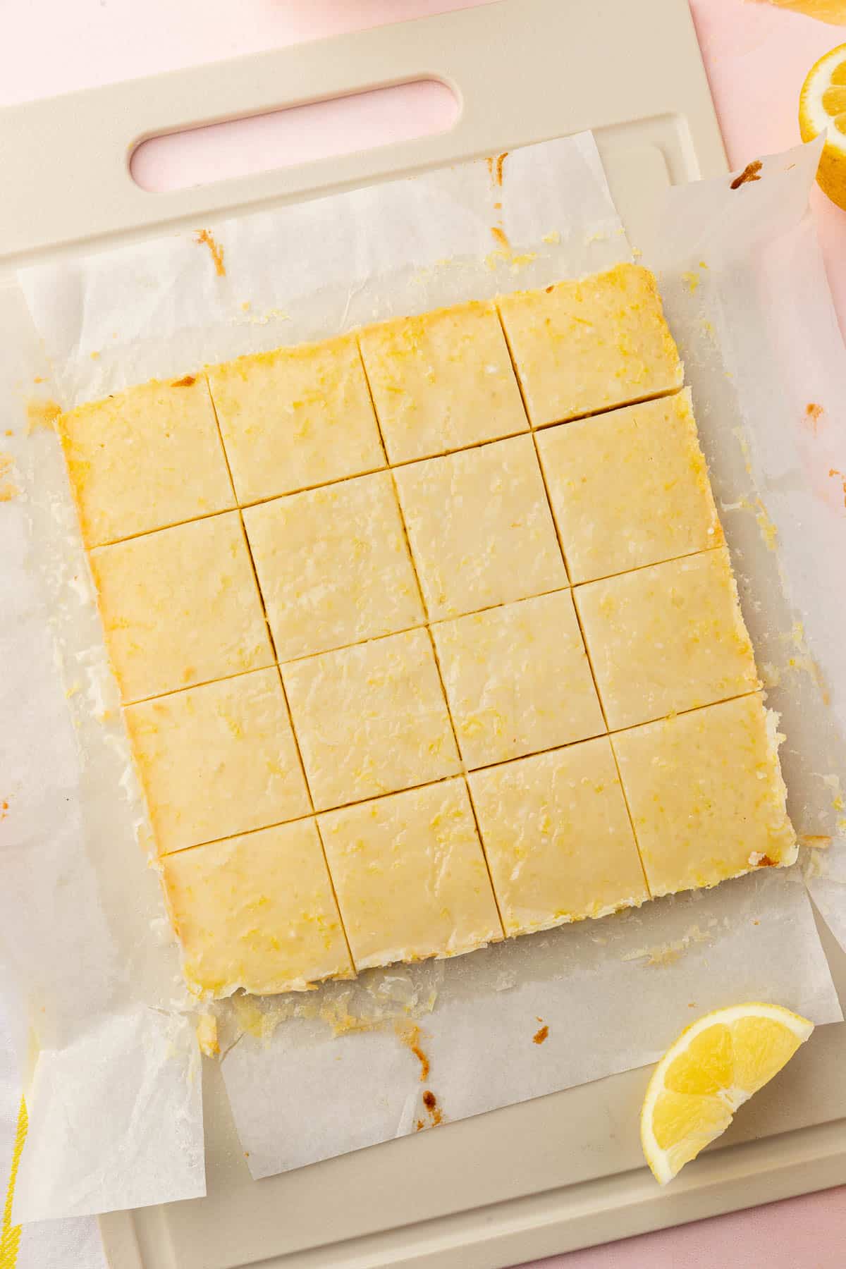 Lemon brownies on a cutting board that have been cut into 16 equal pieces.