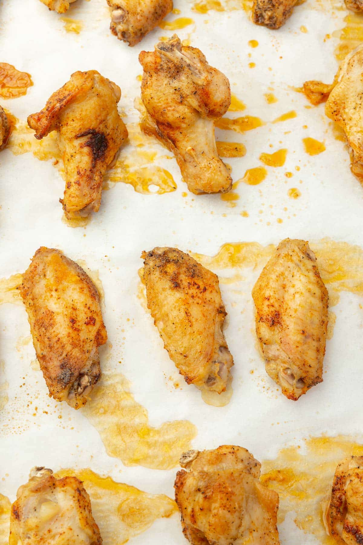 A close up of baked chicken wings on parchment paper.