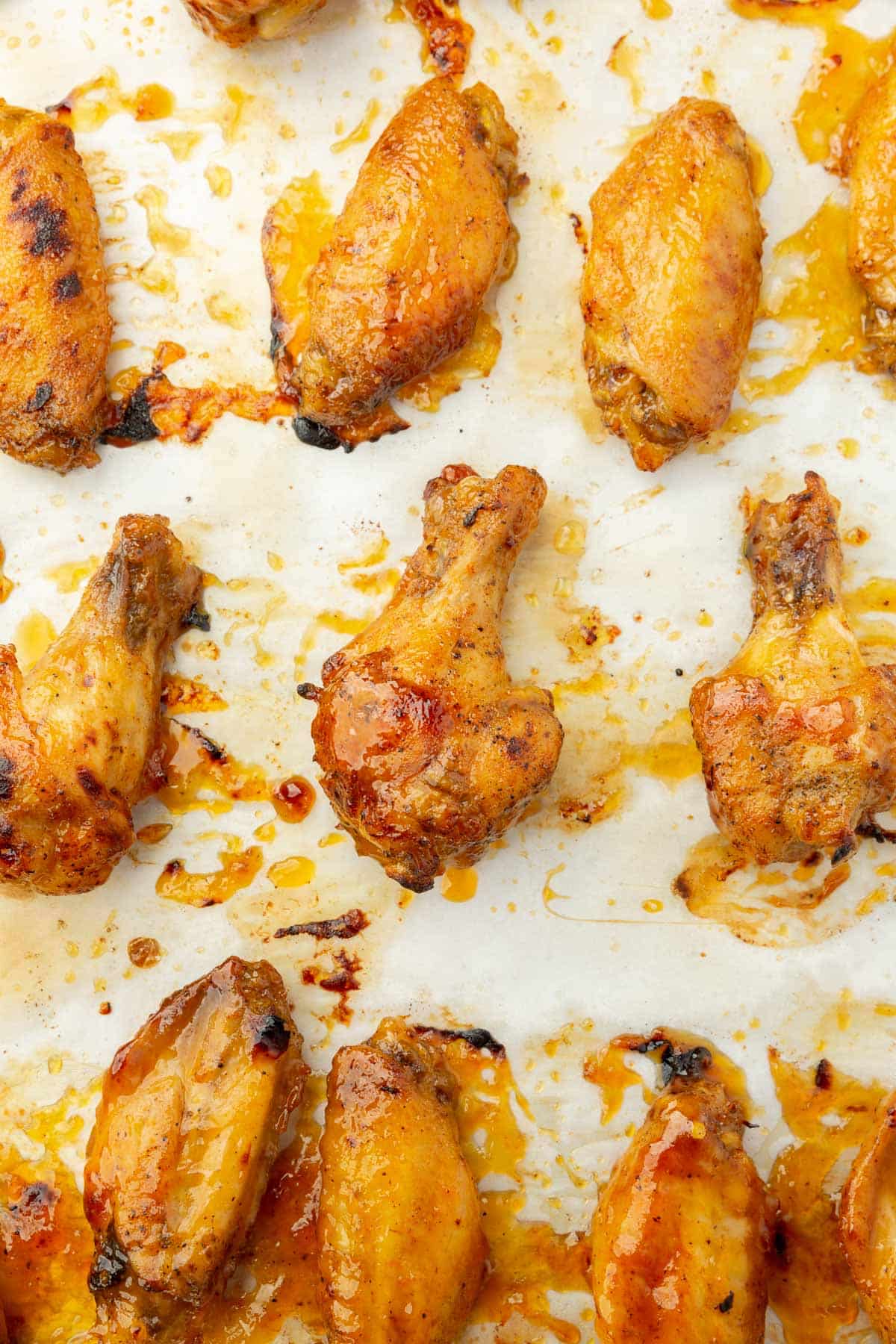 A close up of charred chicken wings on parchment paper.