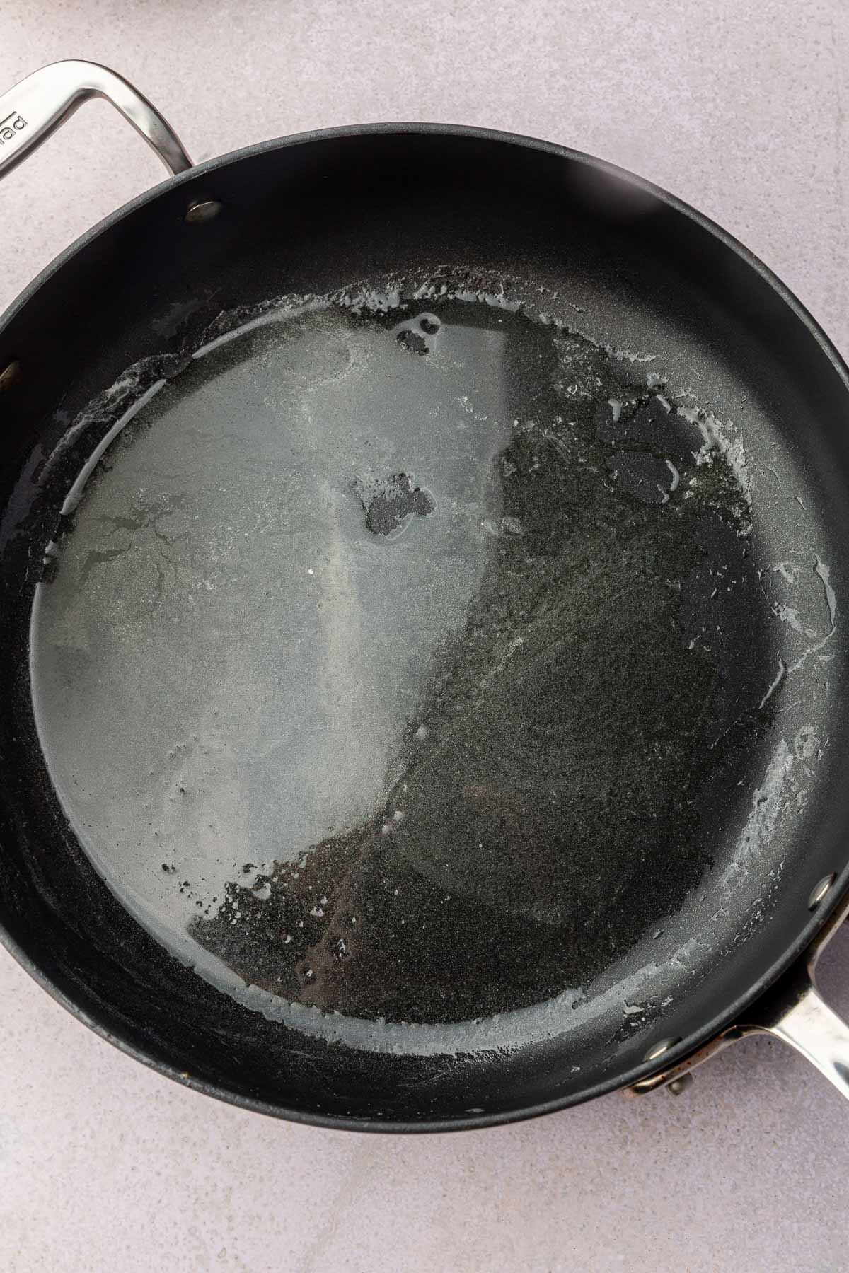 A non-stick skillet with melted butter in it.