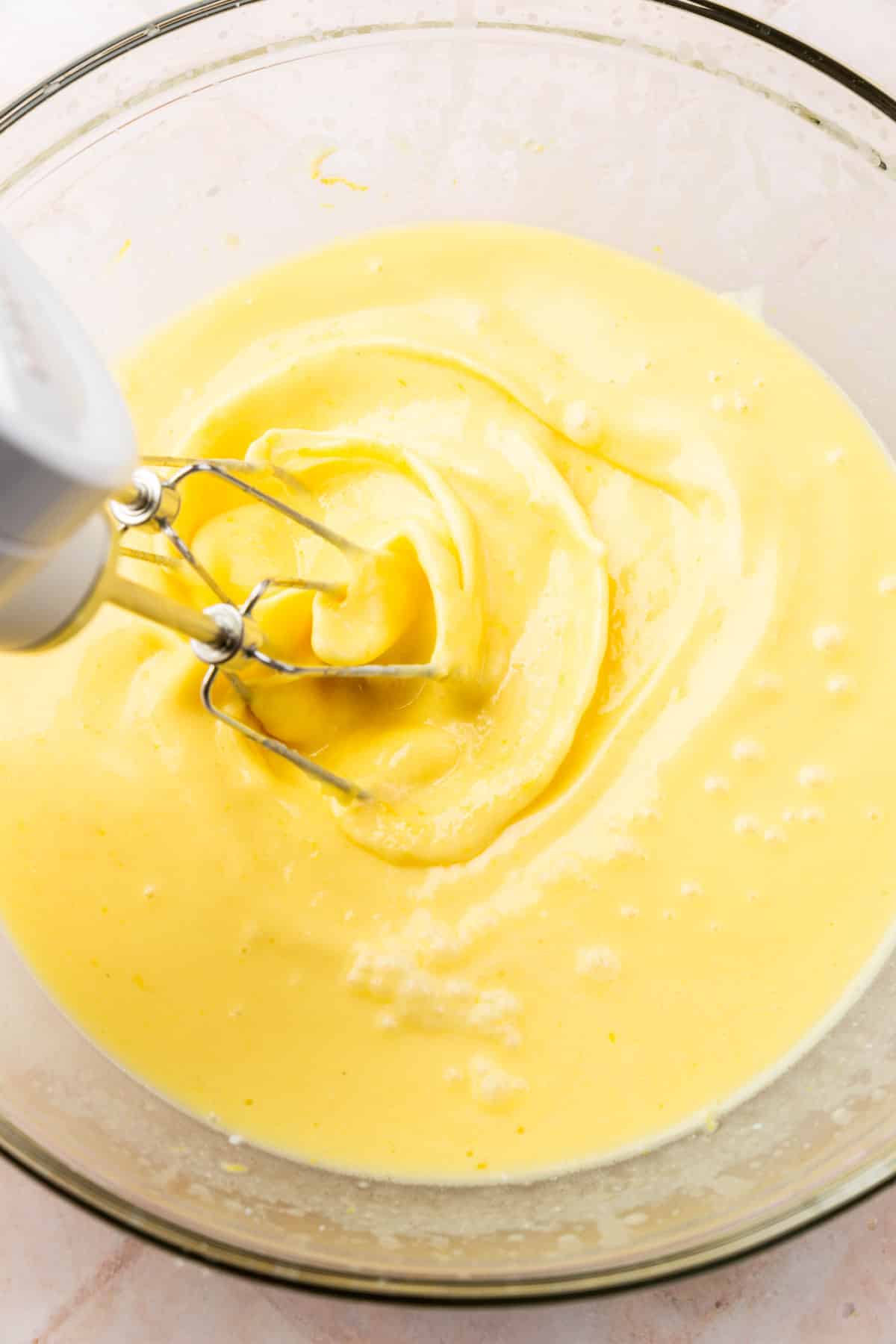 A hand mixer blending together a lemon cake batter.