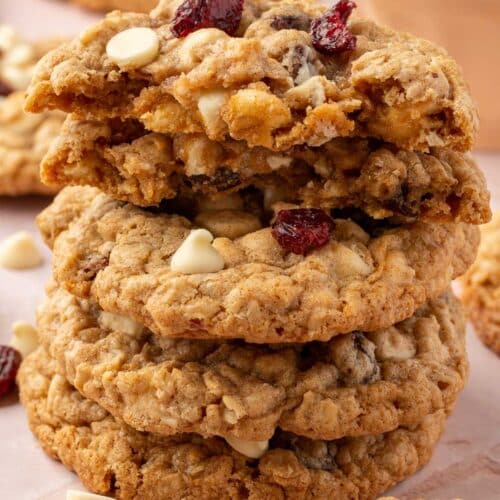 A stack of gluten-free white chocolate oatmeal cranberry cookies with the top two cookies ripped in half to see the inside.