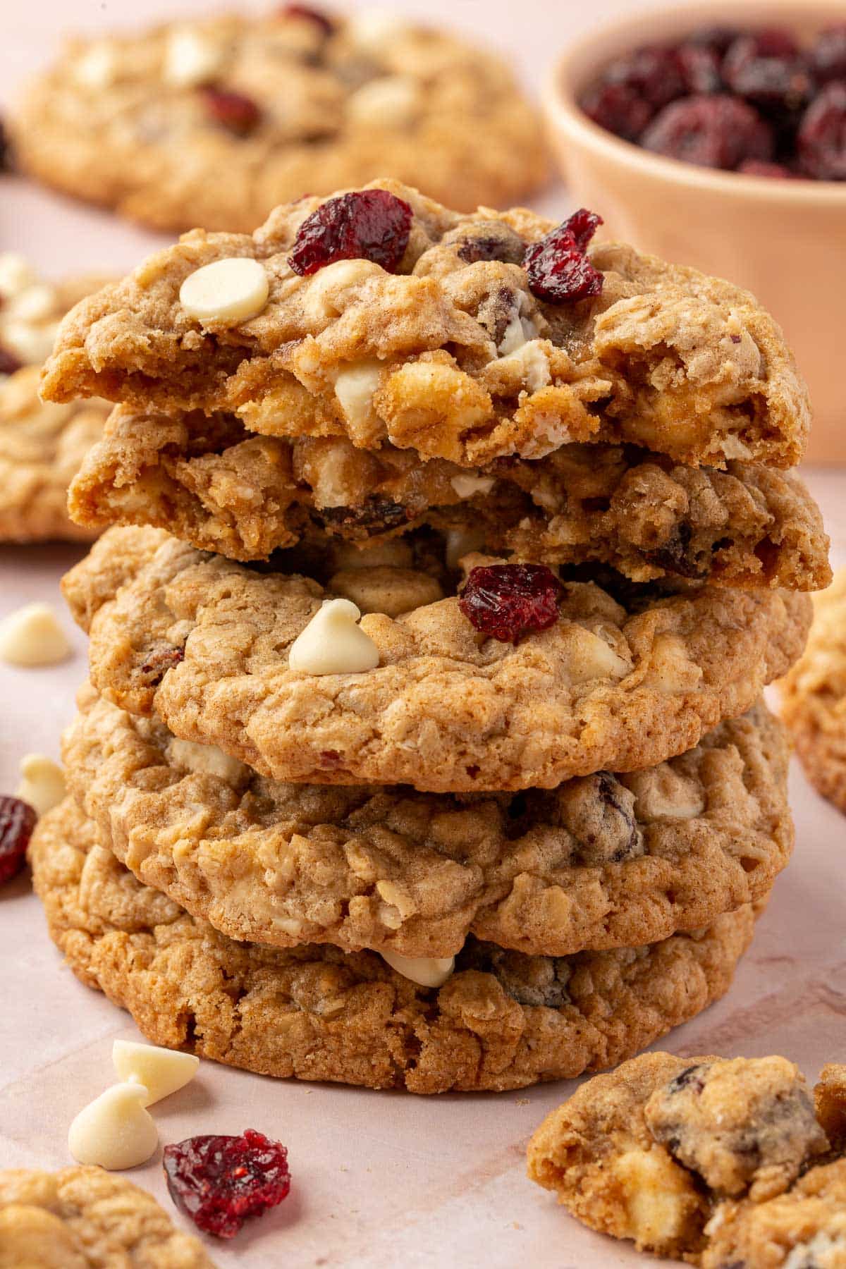 A stack of gluten-free white chocolate oatmeal cranberry cookies with the top two cookies ripped in half to see the inside.