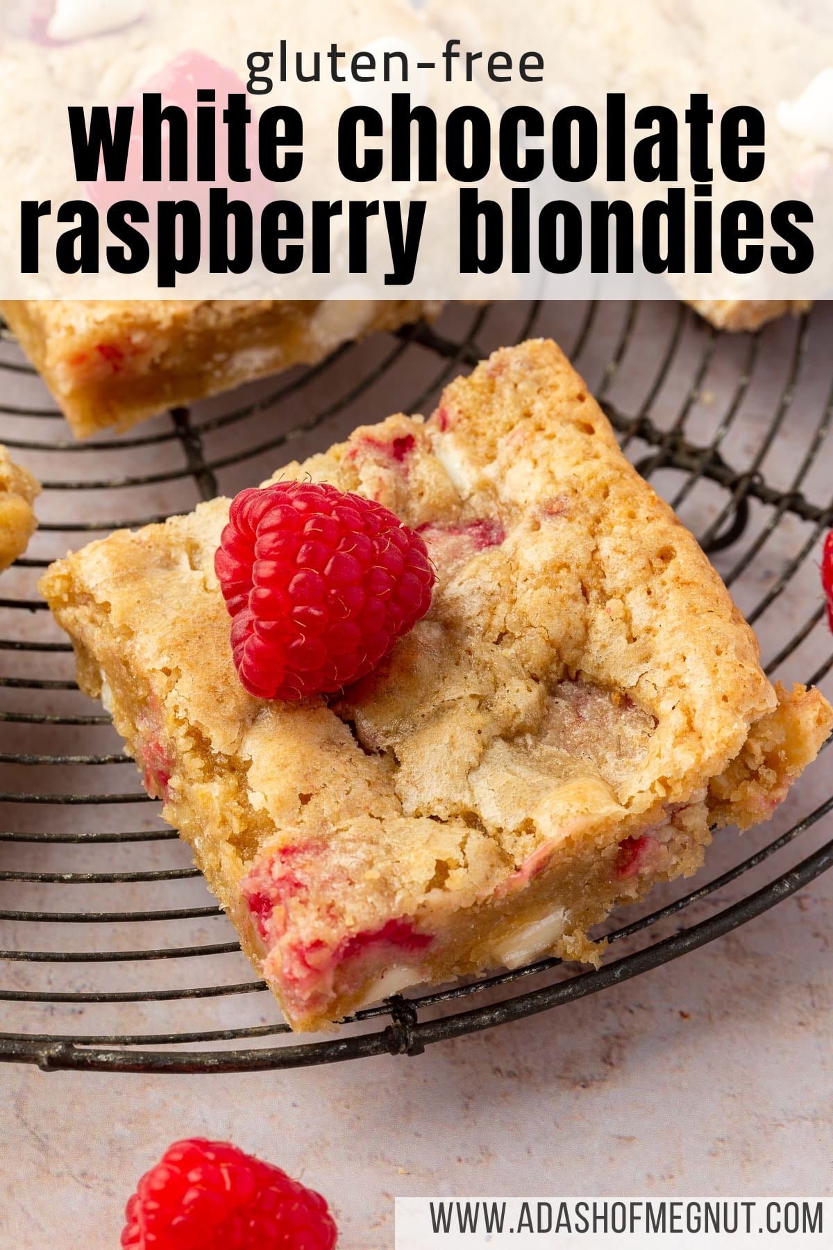 A single gluten free blondie with raspberries and white chocolate chips on a wire cooling rack.