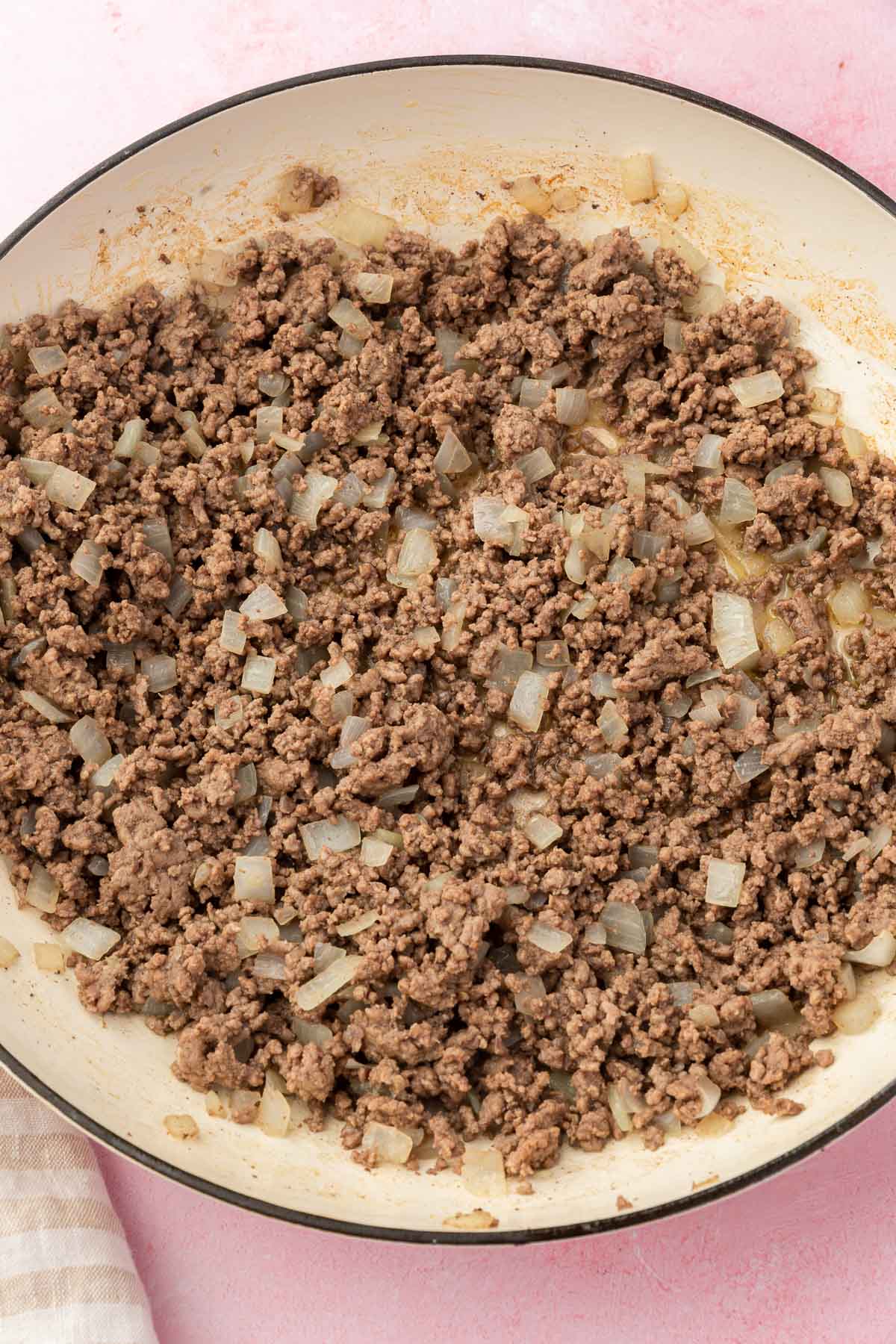 A skillet filled with meat and onions that have been cooked together.
