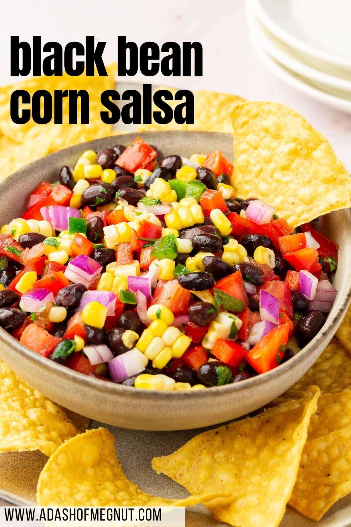 A bowl of black bean corn salsa on a platter of tortilla chips.