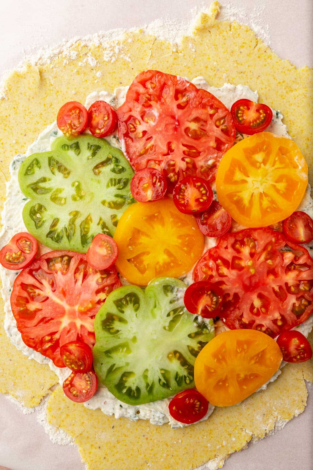 Slices of heirloom tomatoes and cherry tomatoes on a piece of gluten-free tart dough.