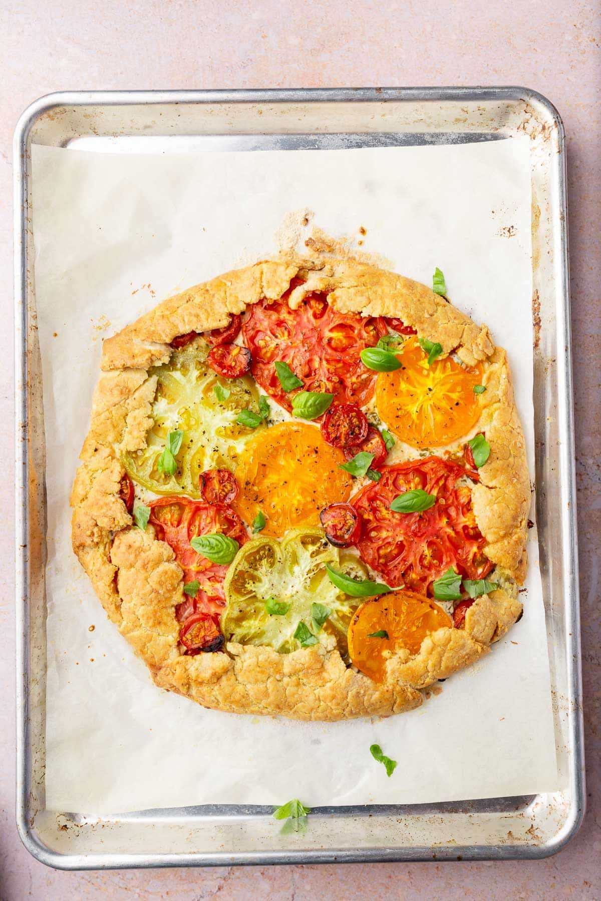 A tomato basil galette on a sheet pan lined with parchment paper.
