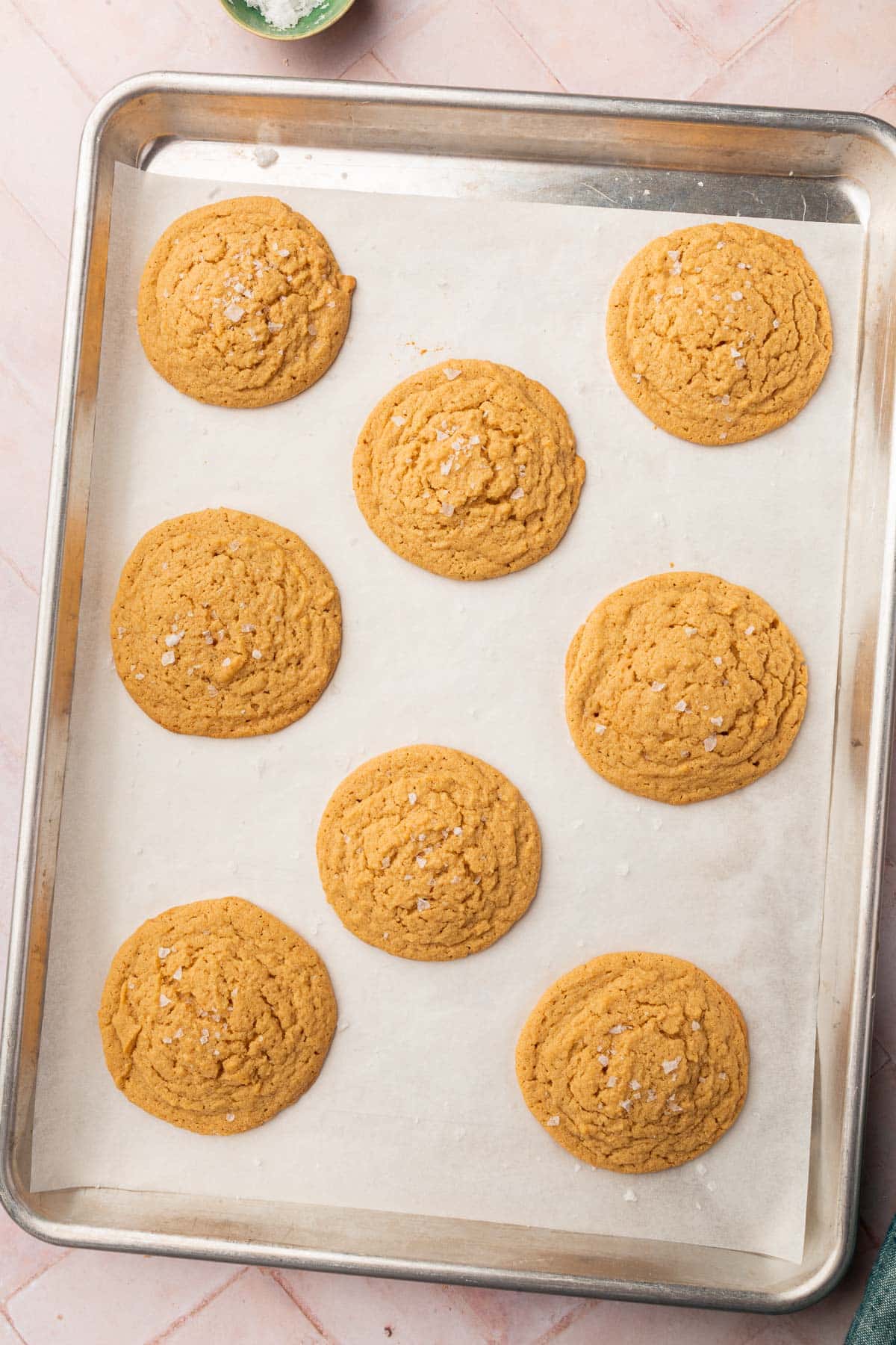 Eight gluten-free peanut butter cookies on a baking sheet lined with parchment paper.