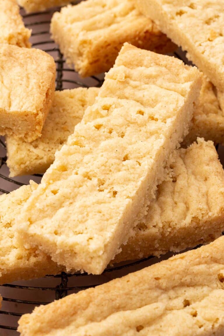 A close up of gluten-free shortbread stacked on top of each other on a wire cooling rack.