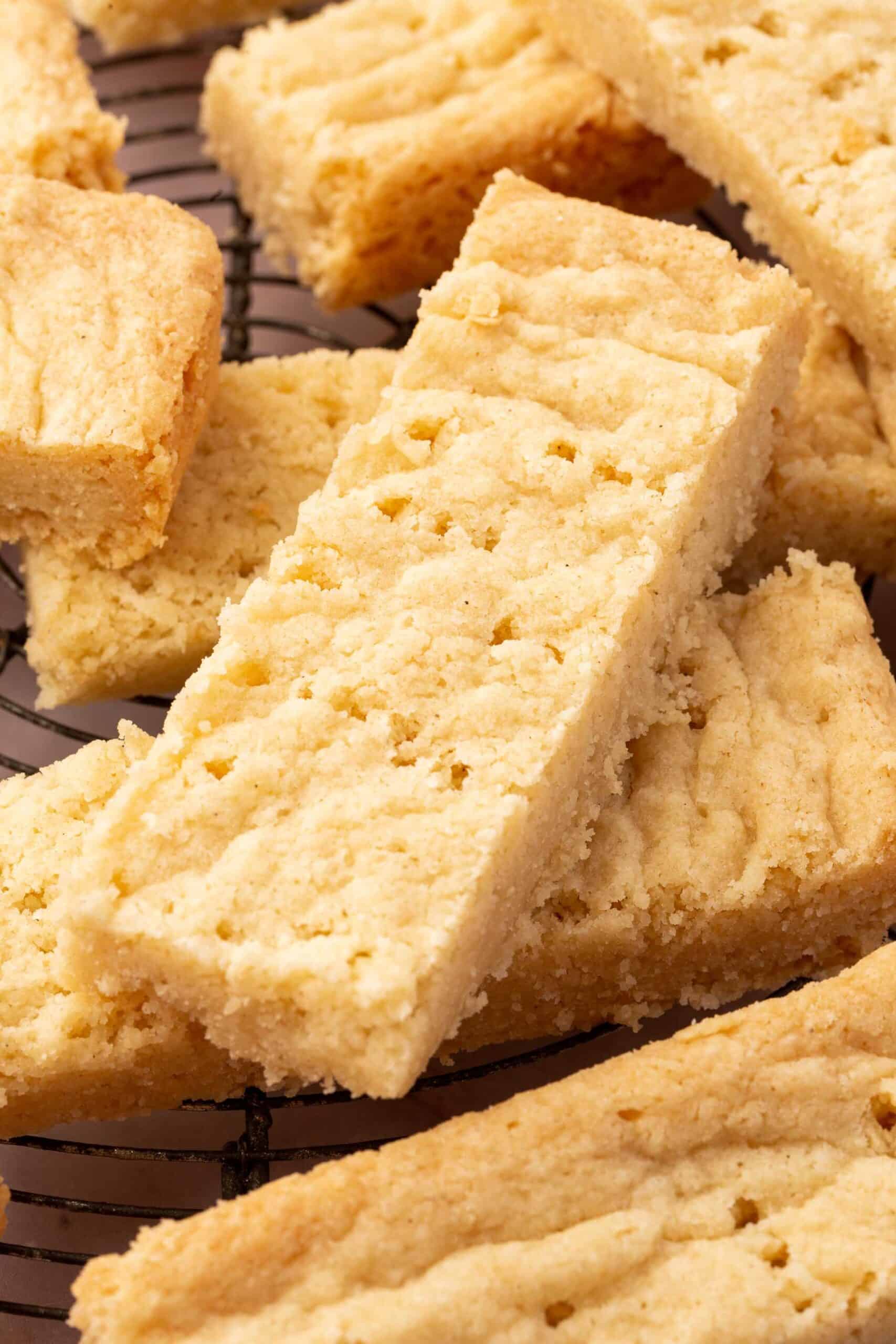 A close up of gluten-free shortbread stacked on top of each other on a wire cooling rack.