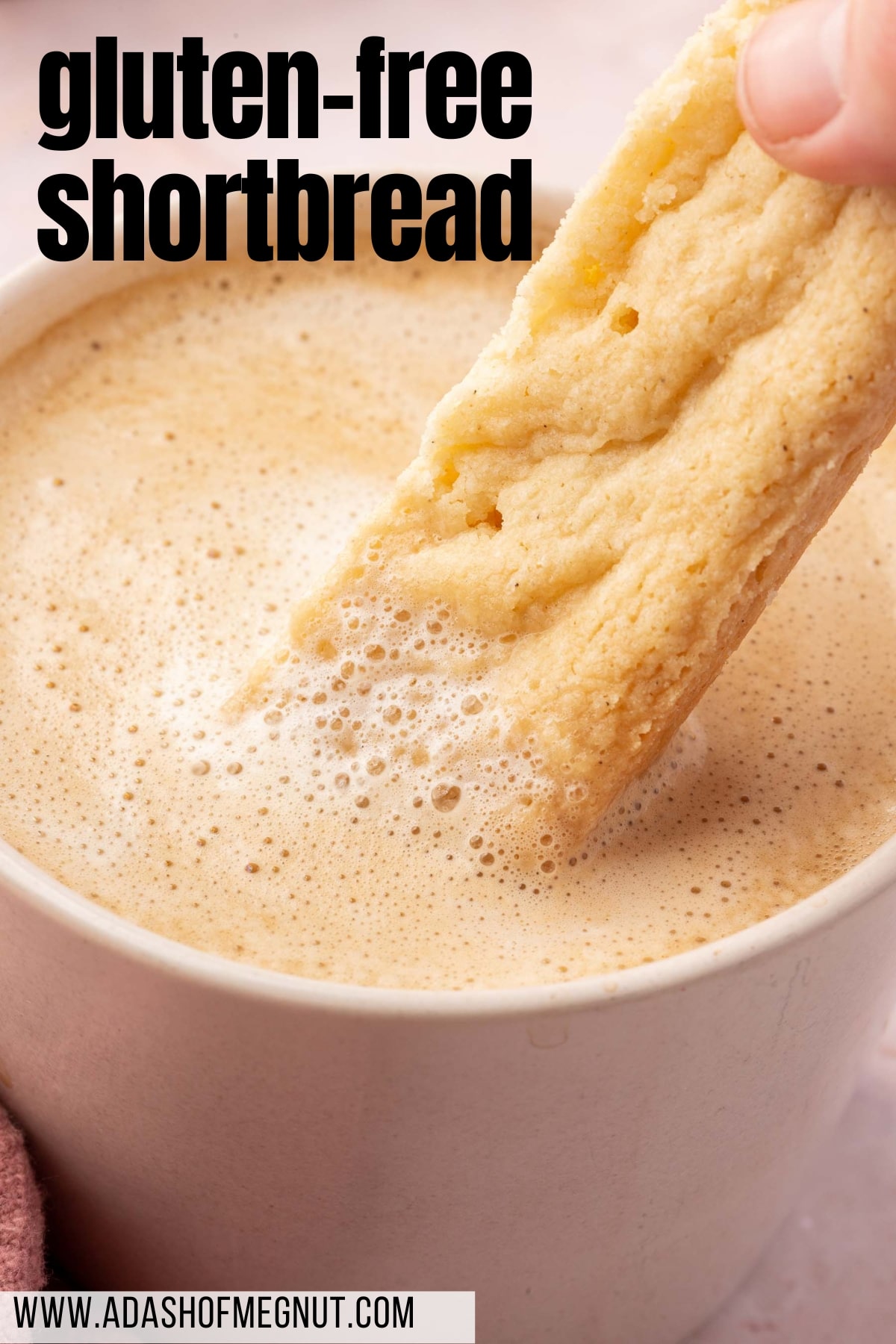 A close up of a gluten-free shortbread finger being dipped into a latte.