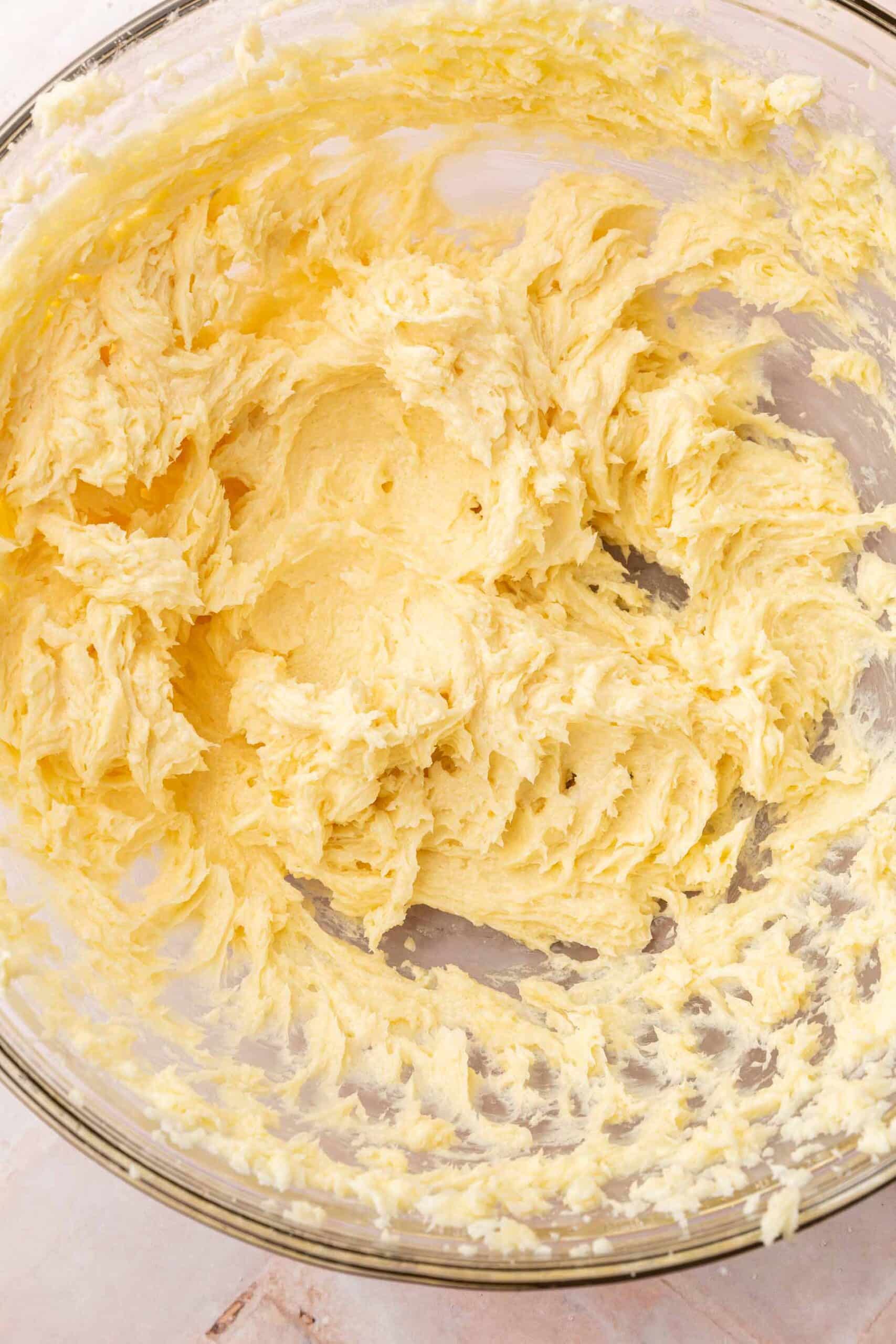 A close up of a glass mixing bowl with creamed butter and sugar in it.