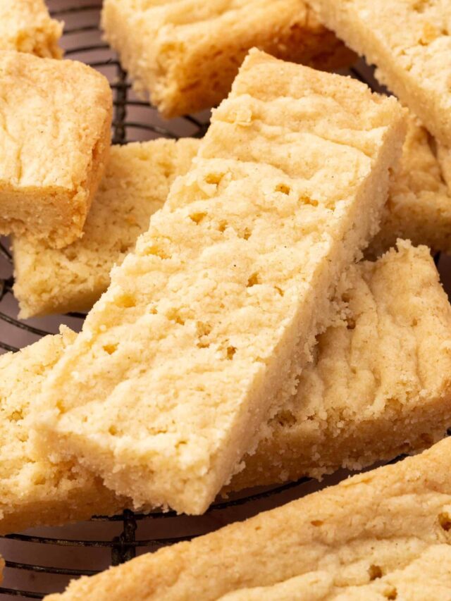 A close up of gluten-free shortbread stacked on top of each other on a wire cooling rack.