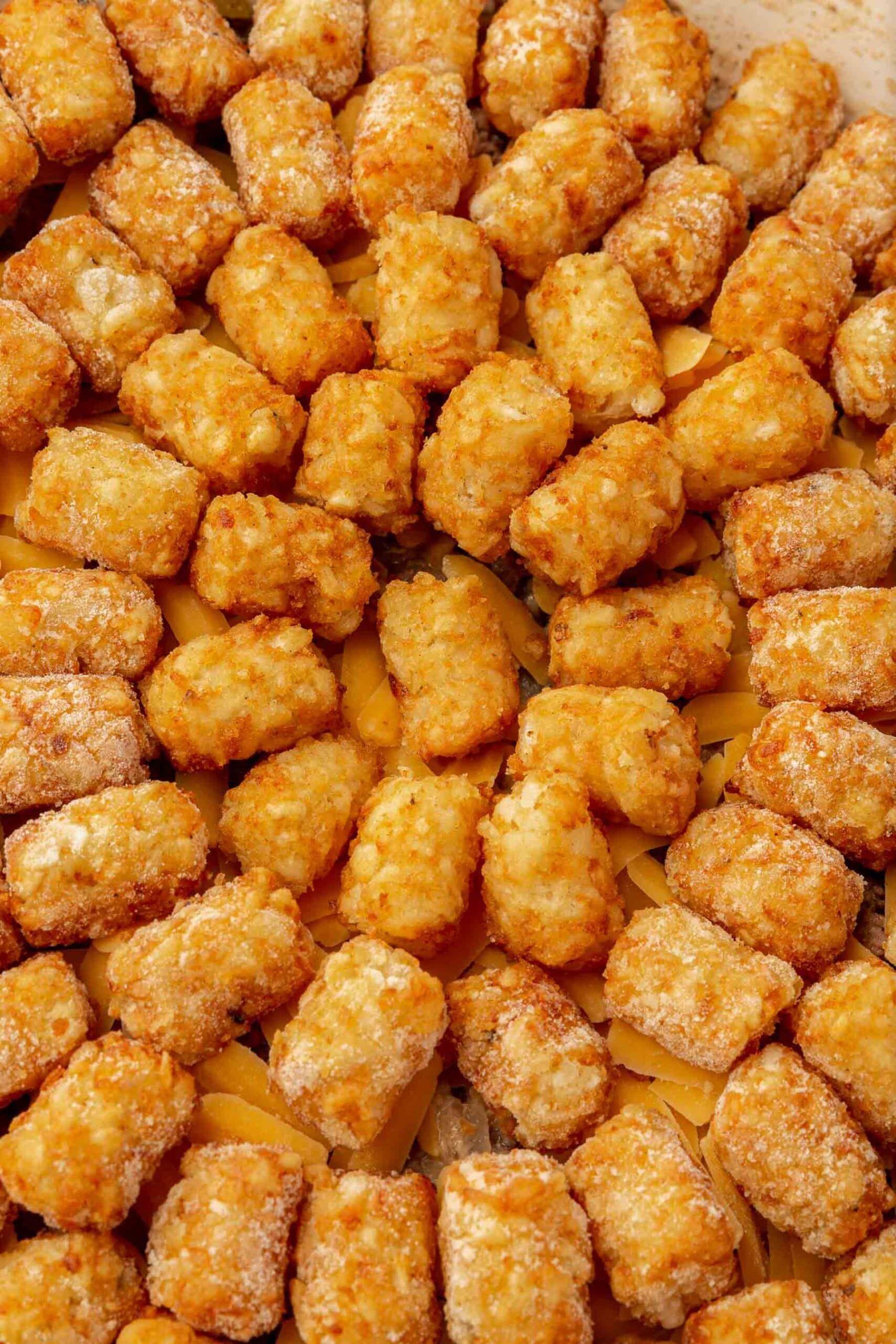 A close up of frozen tater tots arranged in a circle over a casserole.