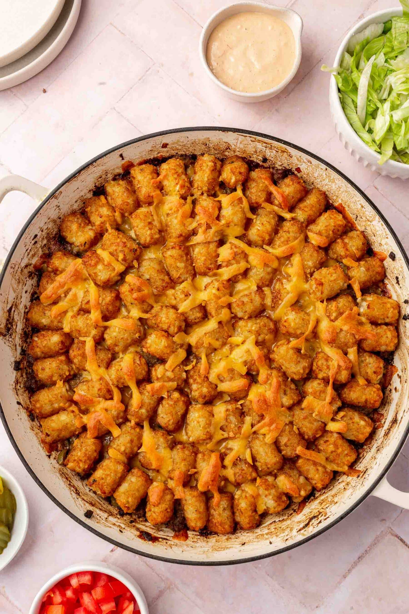 A big mac tater tot casserole in a round white braising pan.