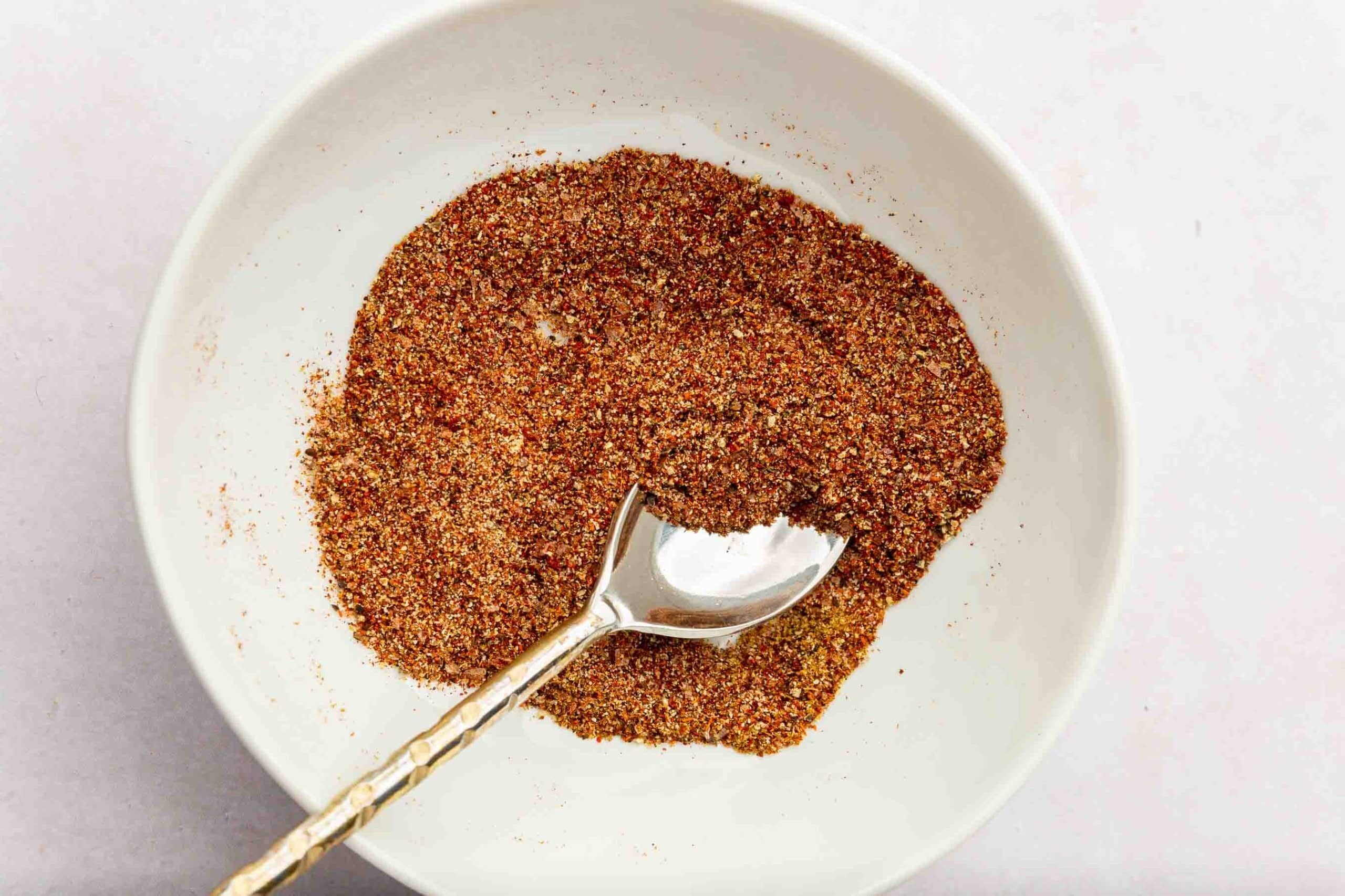 A small mixing bowl with a fish taco spice mixture and a small spoon.