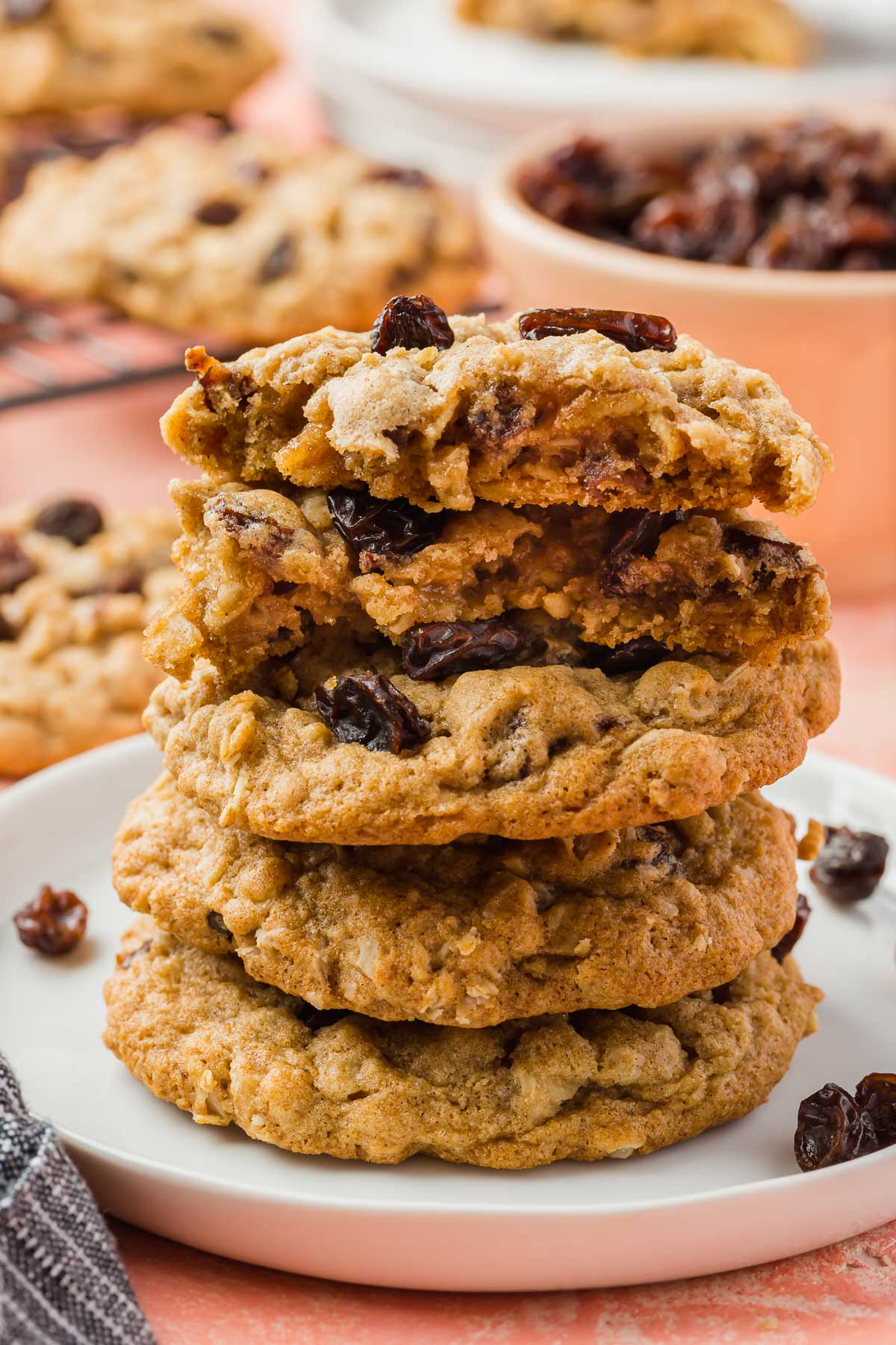 A stack of five gluten free oatmeal raisin cookies on a dessert plate with the top two broken in half to see the chewy interiors.