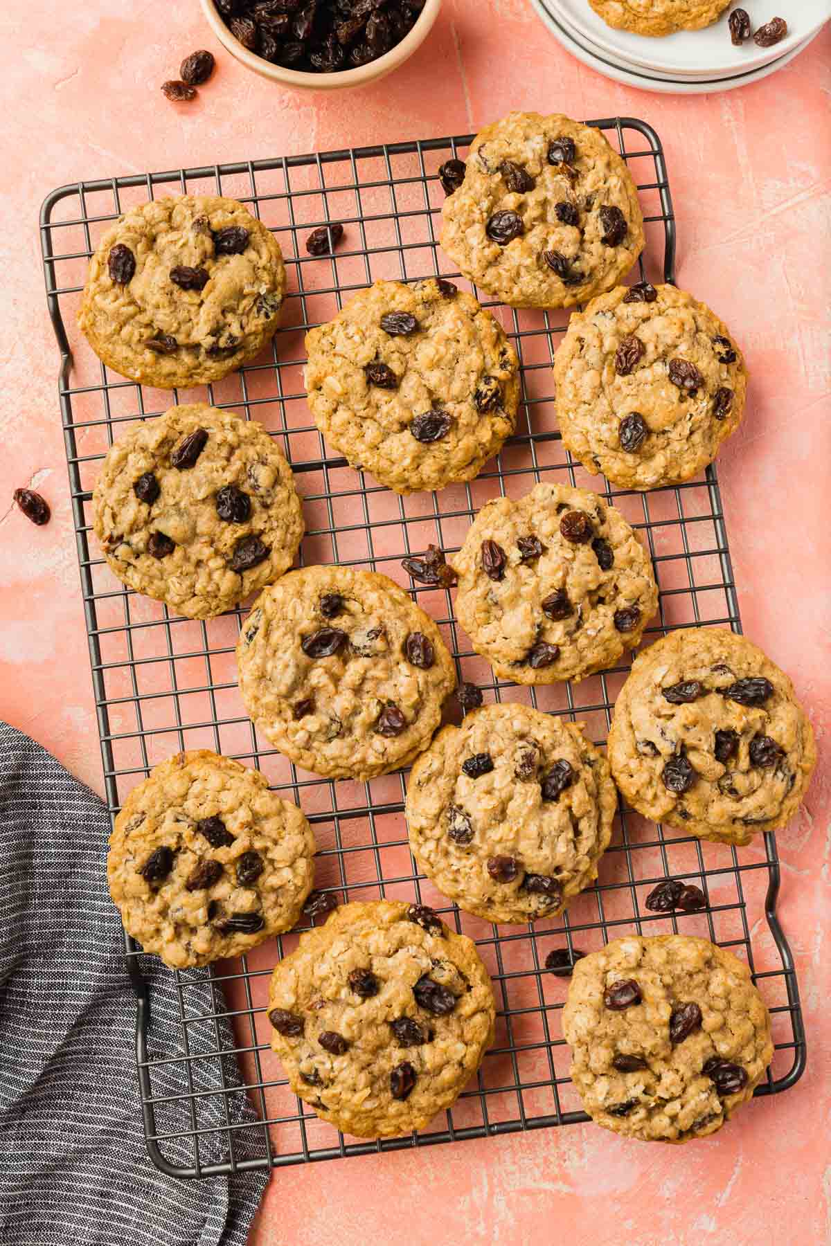 Gluten-free oatmeal raisin cookies on a wire cooling rack on a pink table.