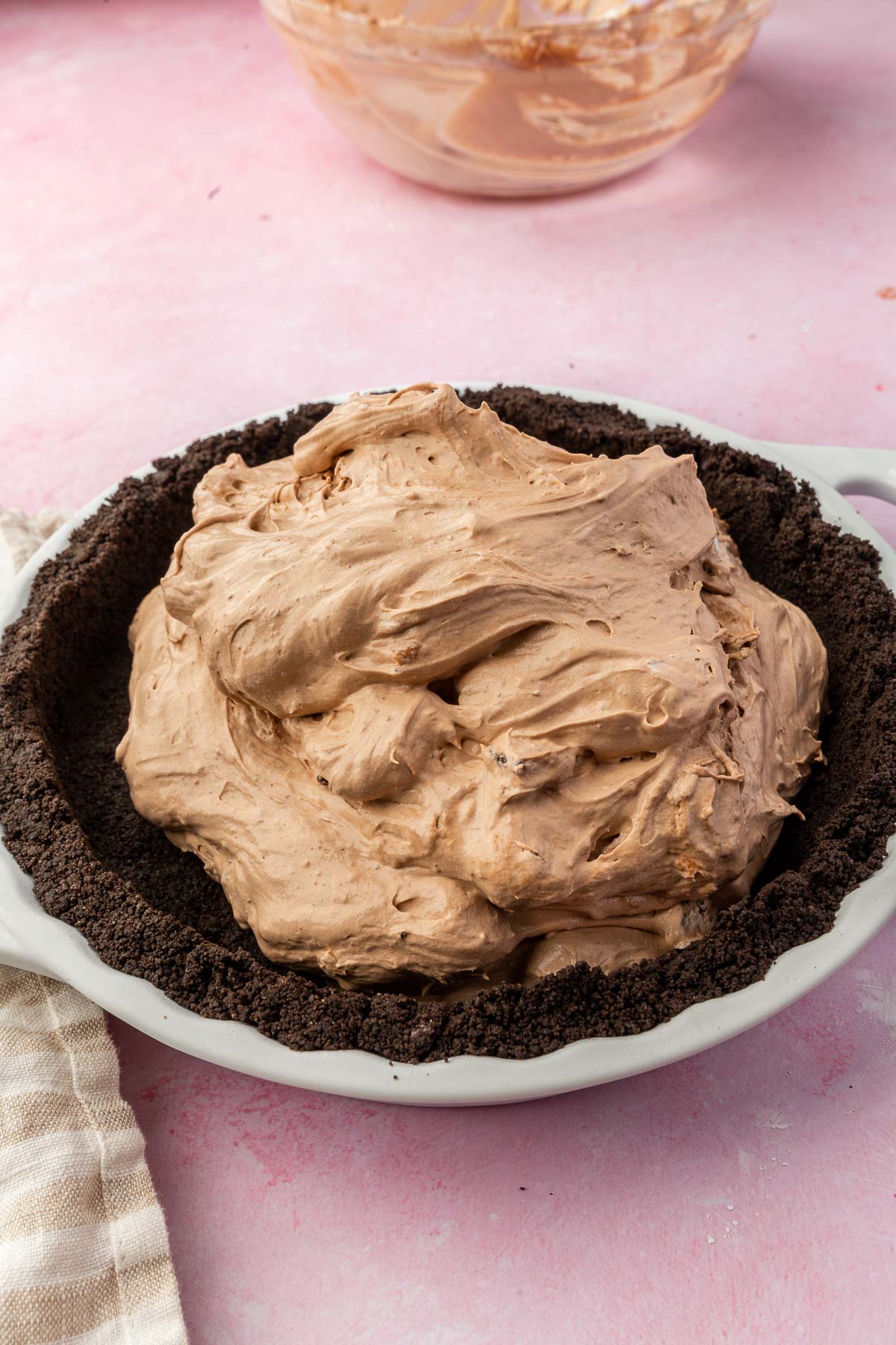 A chocolate whipped cream mixture spread onto a gluten-free Oreo pie crust in a white tart pan.