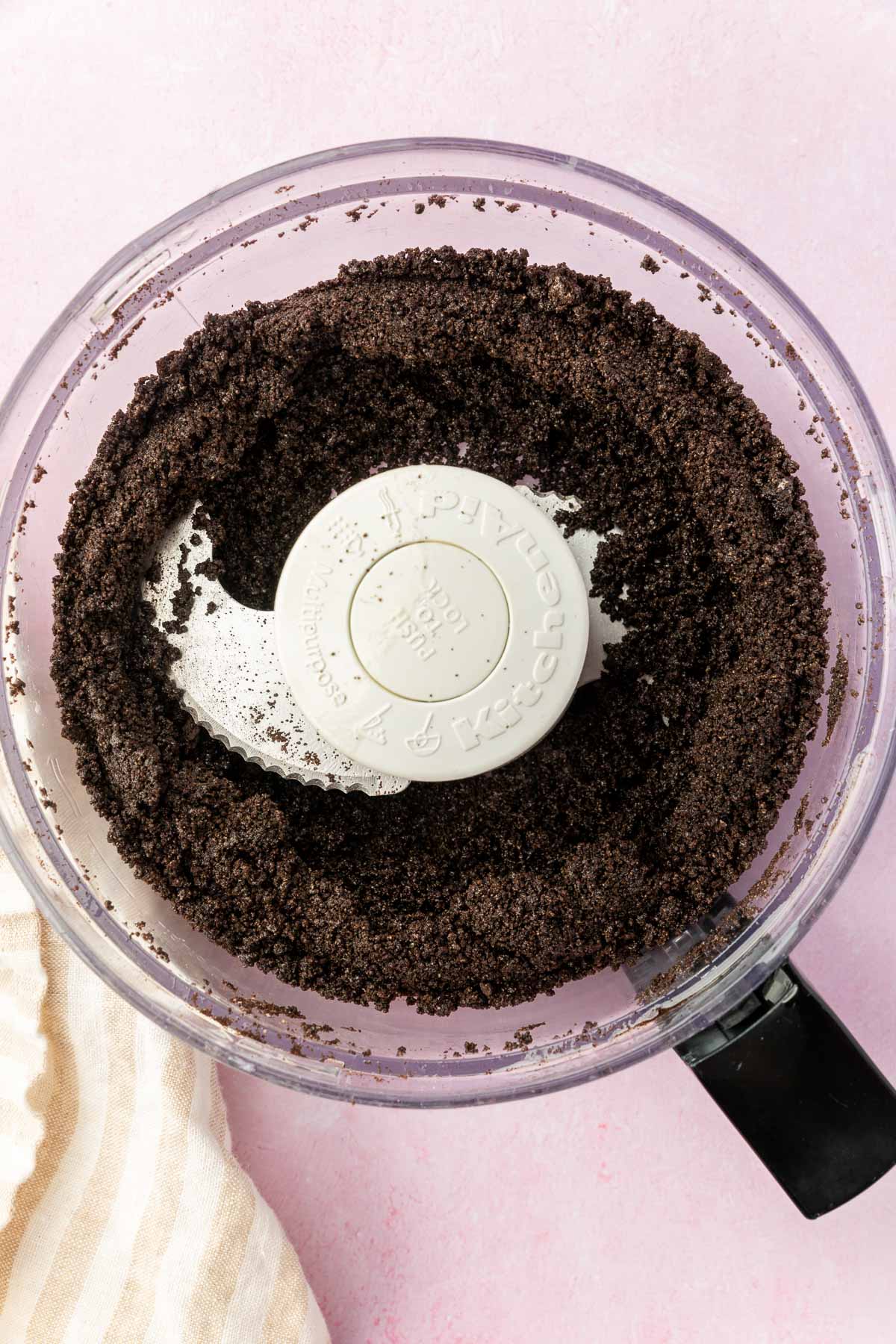 A food processor with gluten-free Oreo crumbs and melted butter mixed together to make an Oreo pie crust.