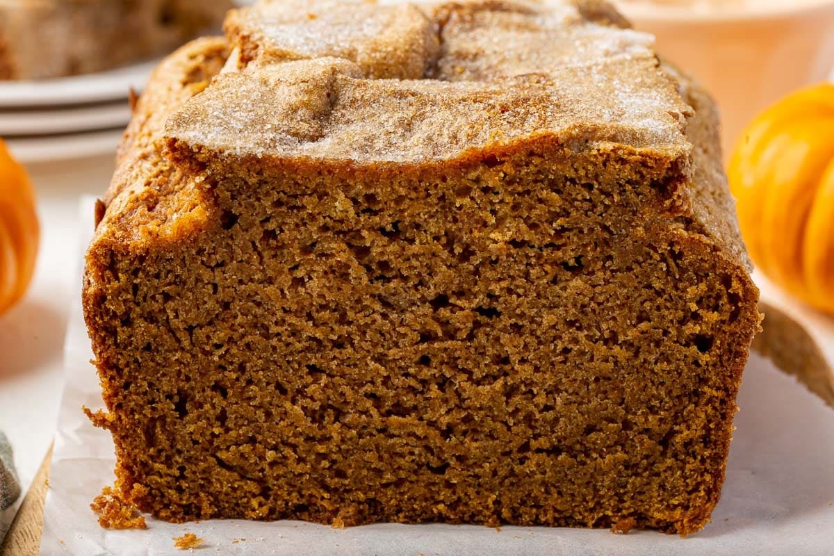 A close up of a loaf of gluten-free pumpkin bread that has been partially sliced.
