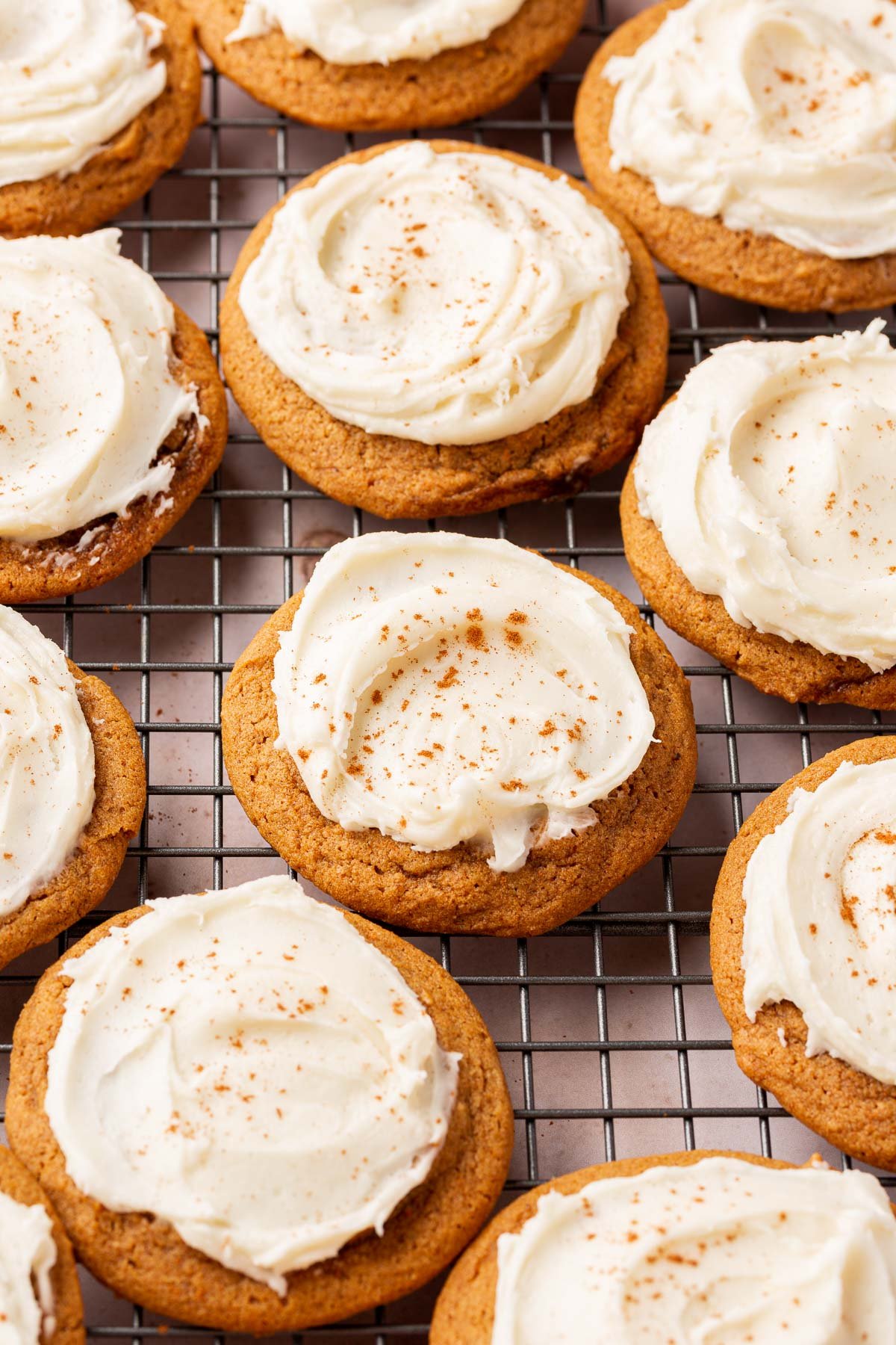 Gluten-free pumpkin cookies with cream cheese frosting on a wire cooling rack.