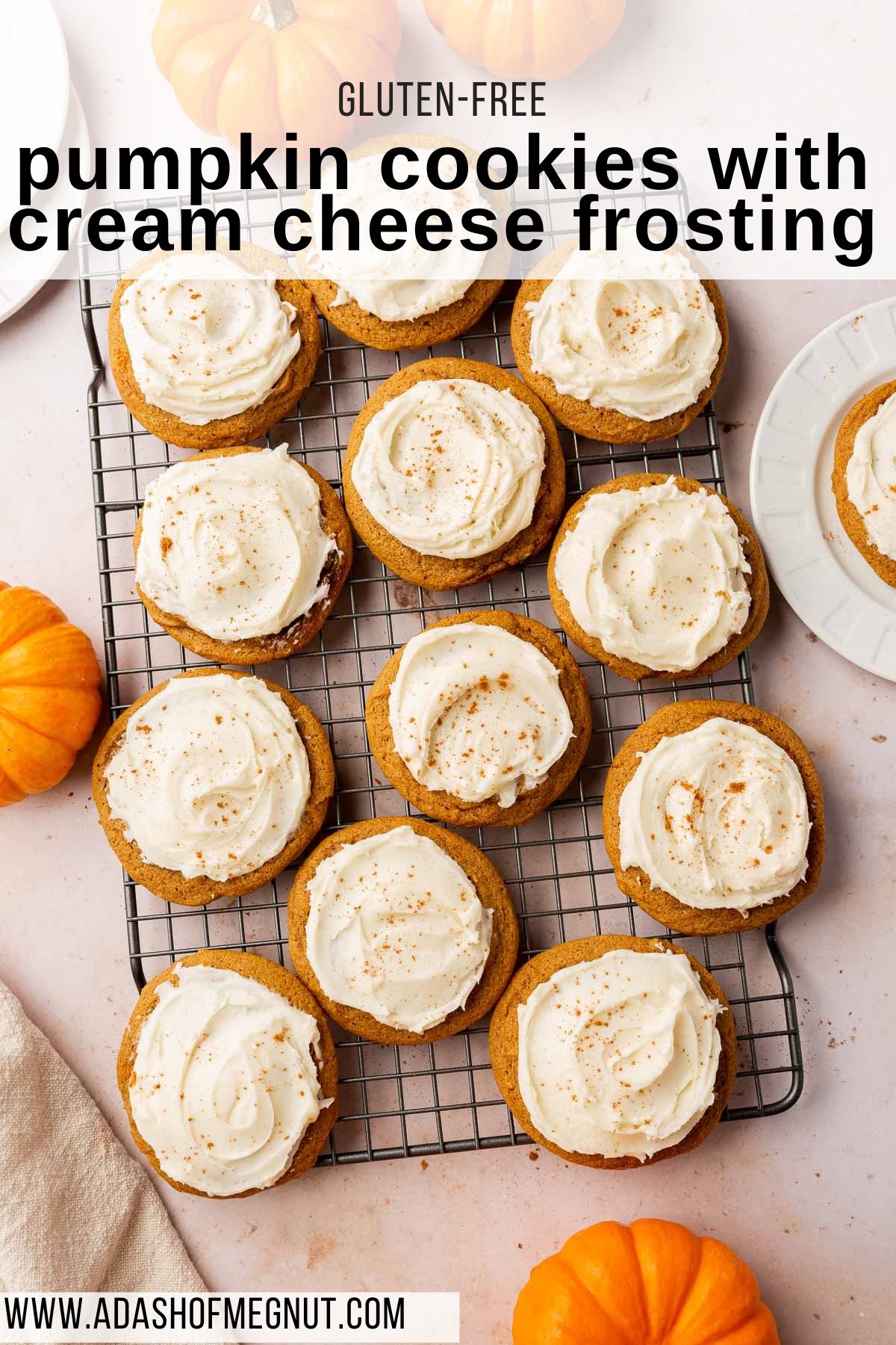 An overhead view of gluten-free pumpkin cookies topped with cream cheese frosting on a wire cooling rack with mini pumpkins surrounding the cookies.