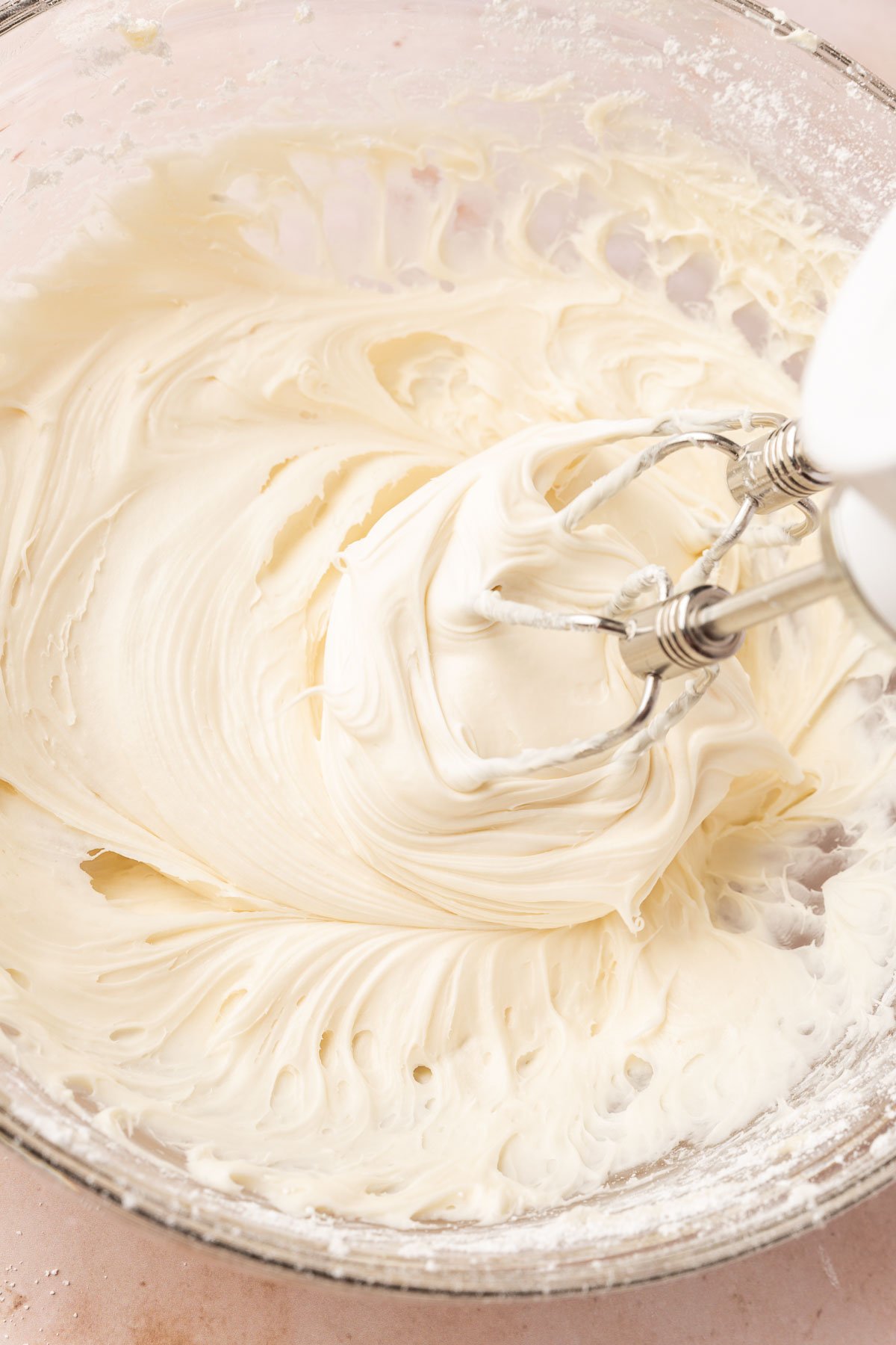 An electric mixer blending together cream cheese frosting.