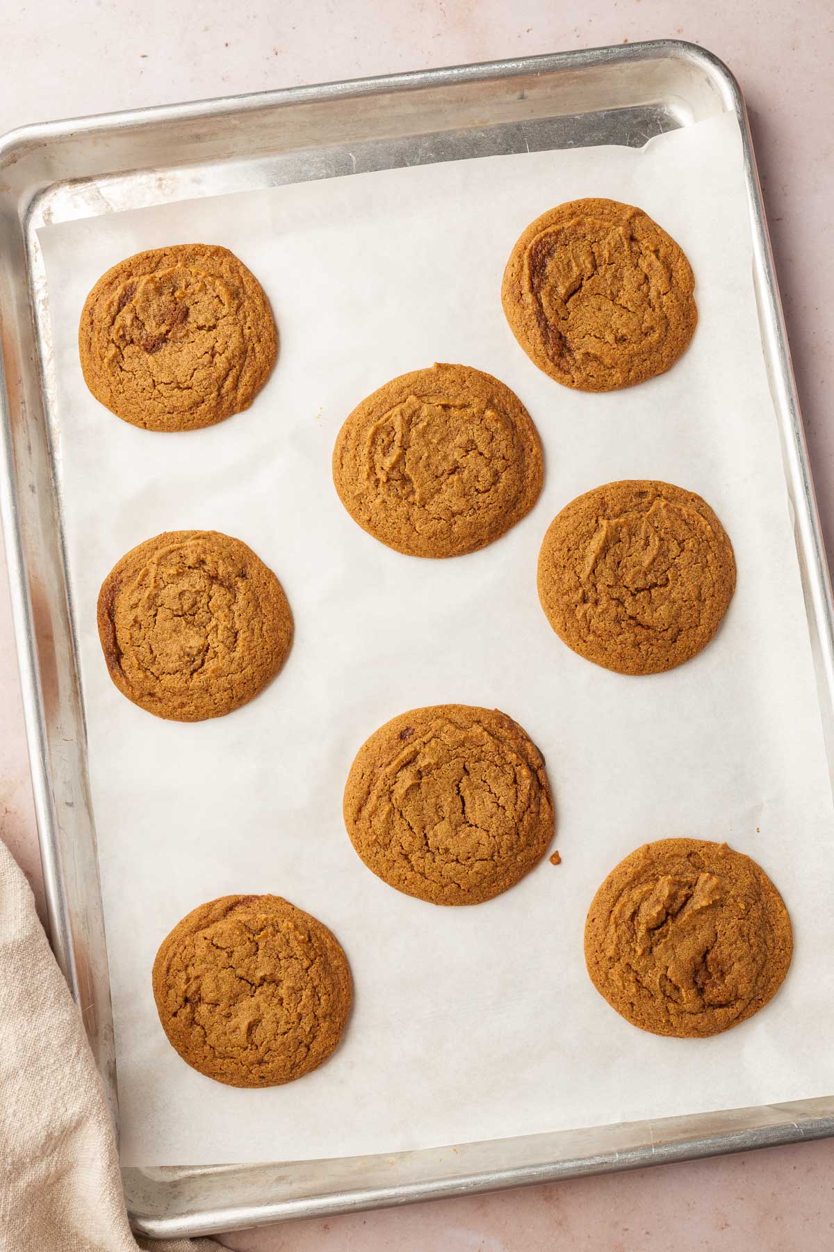Eight gluten-free pumpkin cookies on a baking sheet lined with parchment paper.