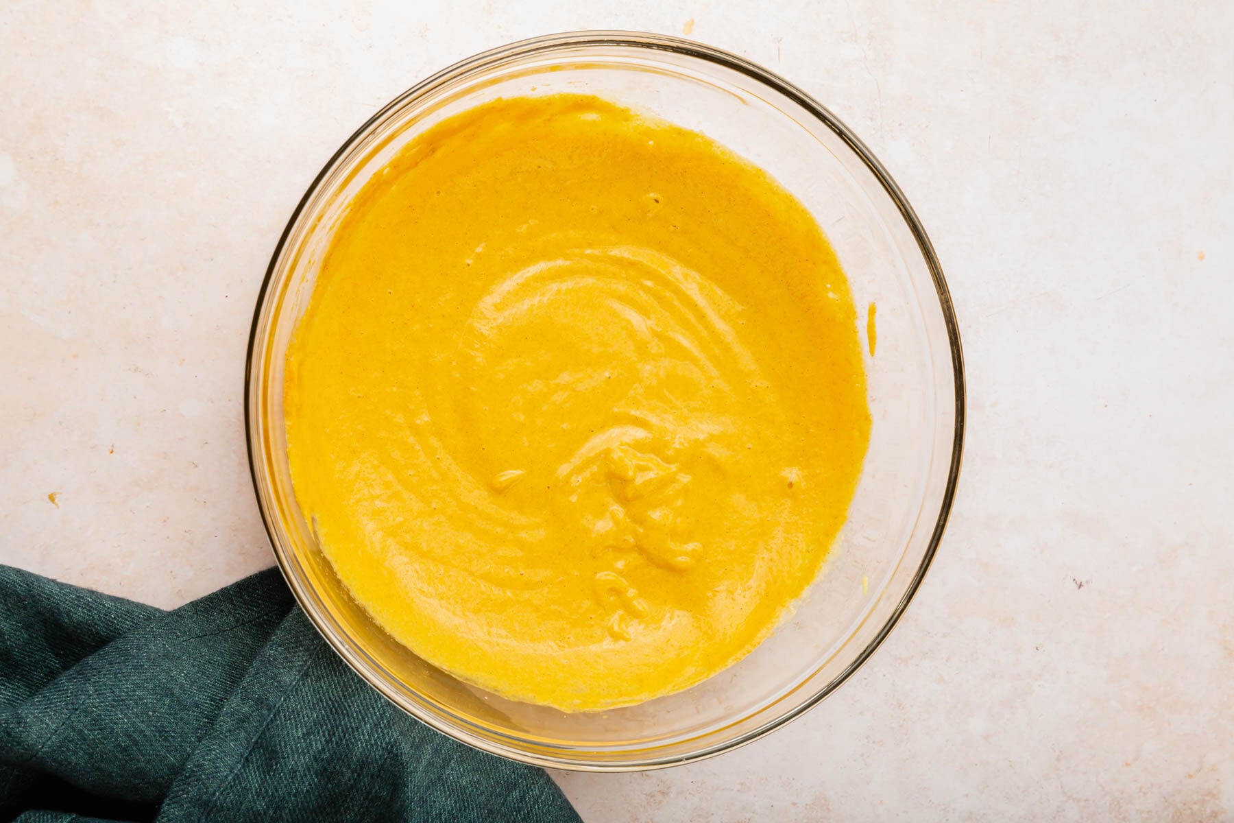 A glass mixing bowl with pumpkin creme brulee mixture in it.