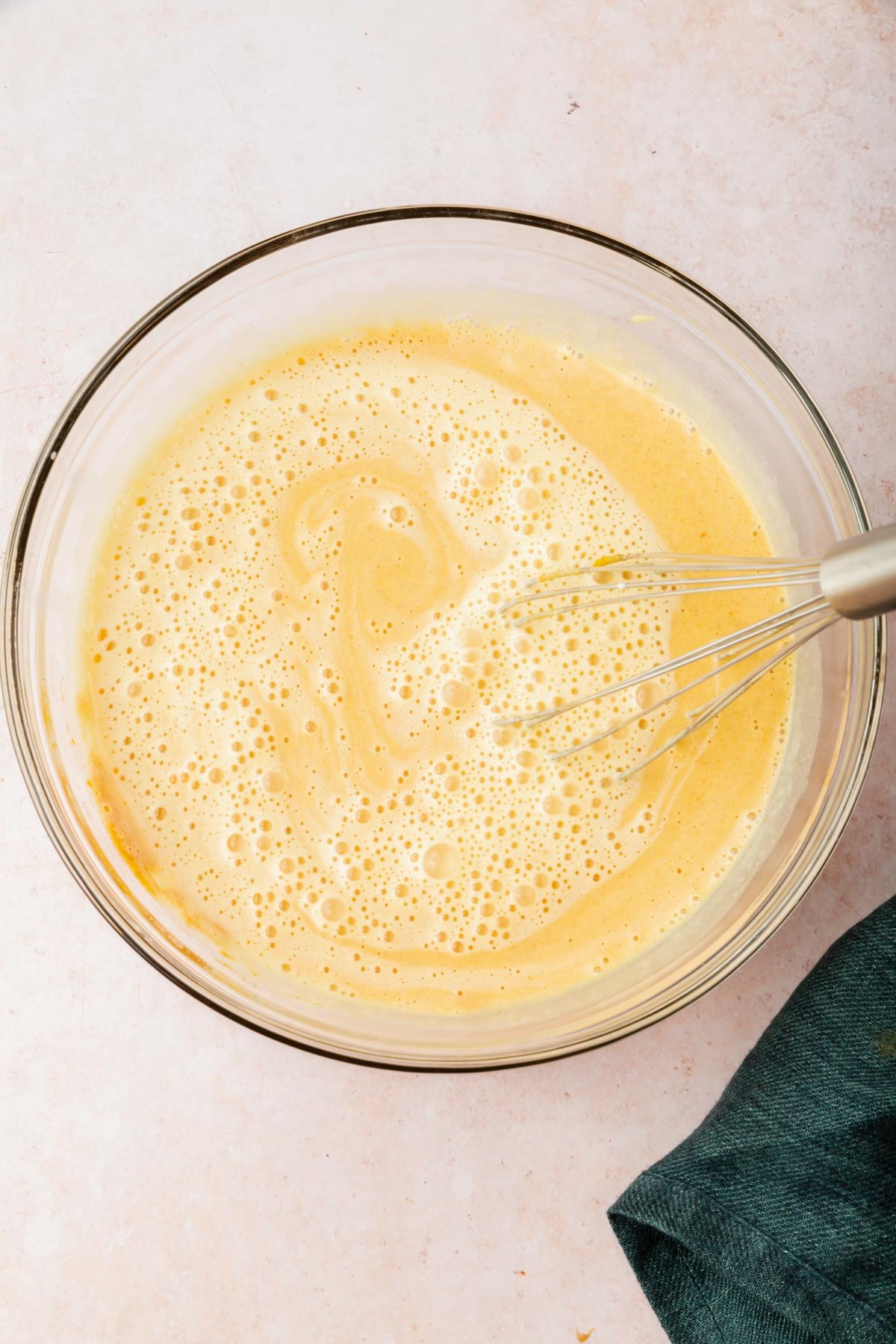 A glass mixing bowl with pumpkin crème brûlée mixture with a wire whisk.