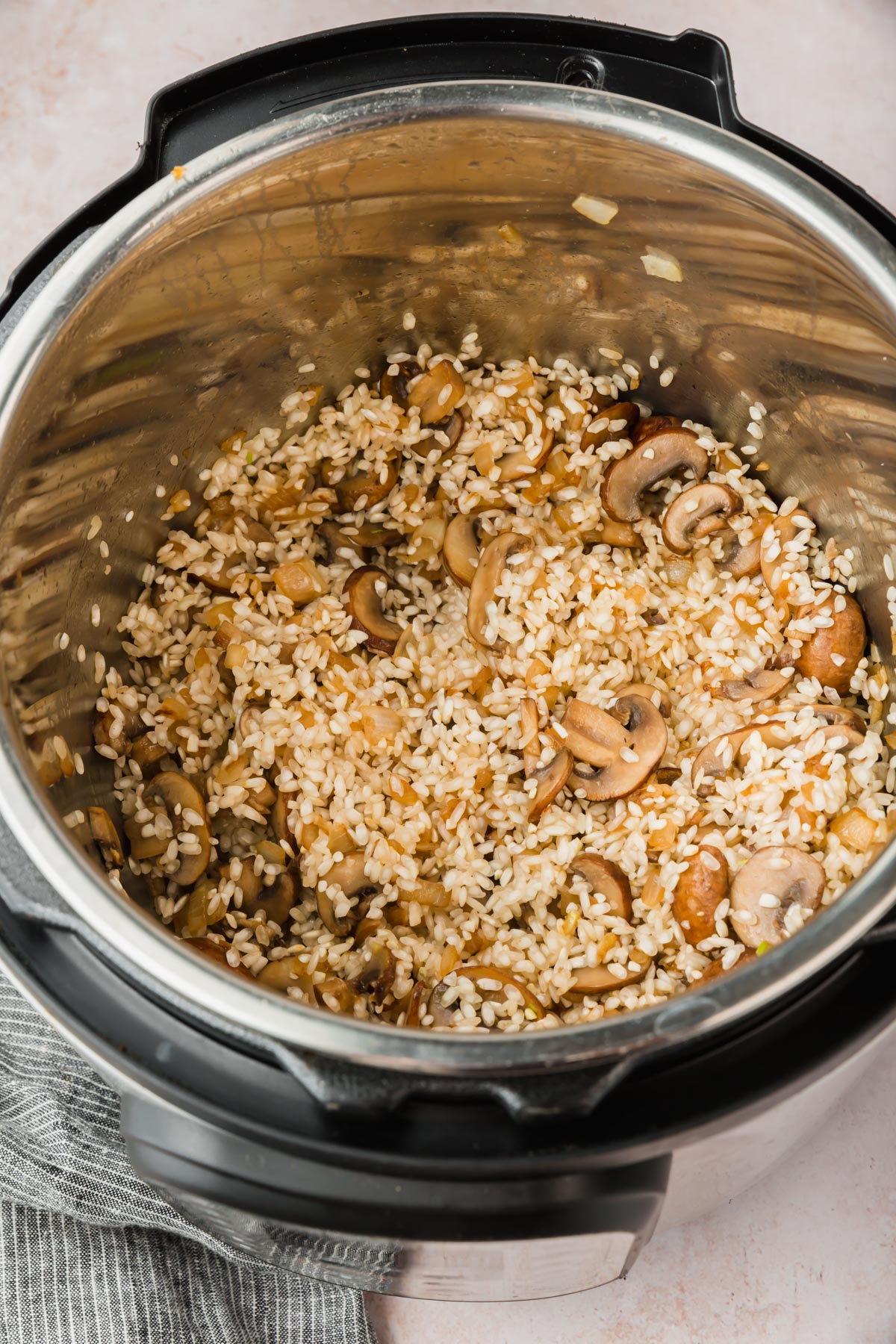 An Instant Pot filled with arborio rice and sautéed mushrooms.