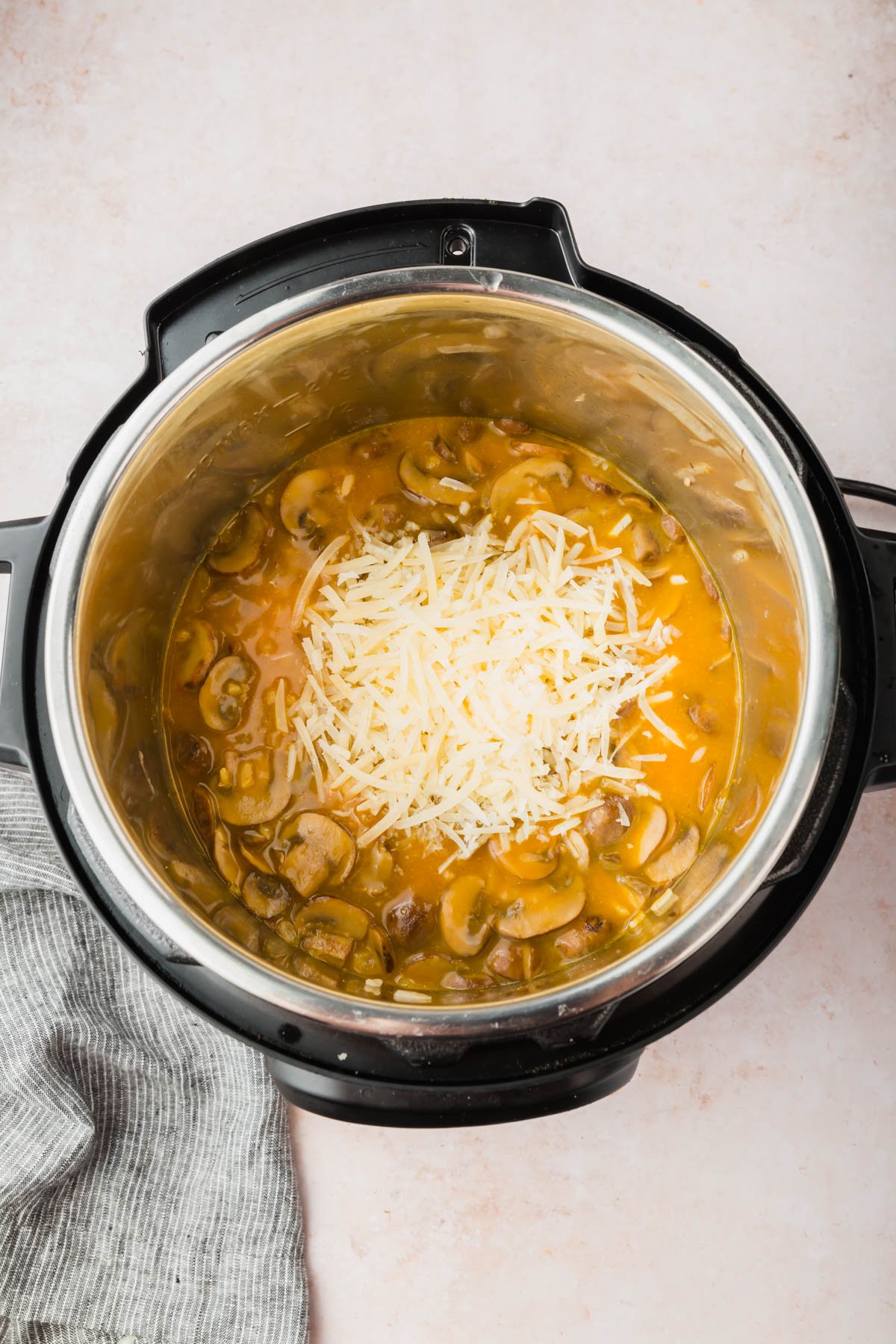 An overhead view of mushrooms in a pumpkin broth topped with shredded parmesan cheese.